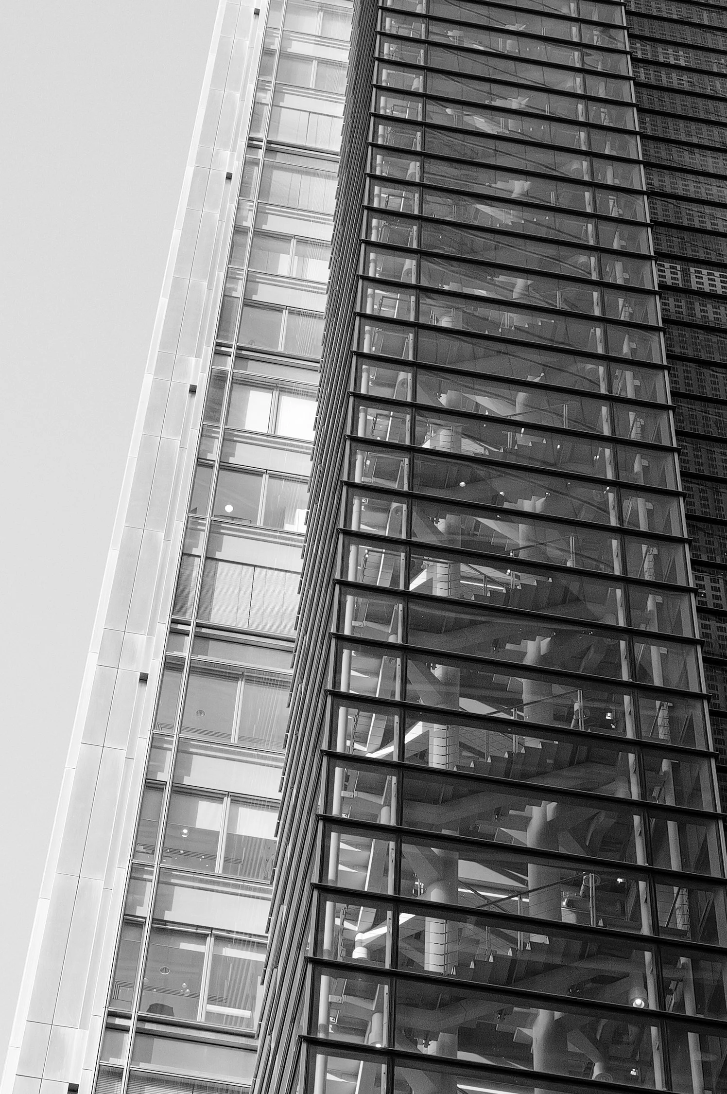 Facade en verre d'un immeuble moderne vue de dessous, avec plusieurs étages visibles et un motif de lignes horizontales et verticales