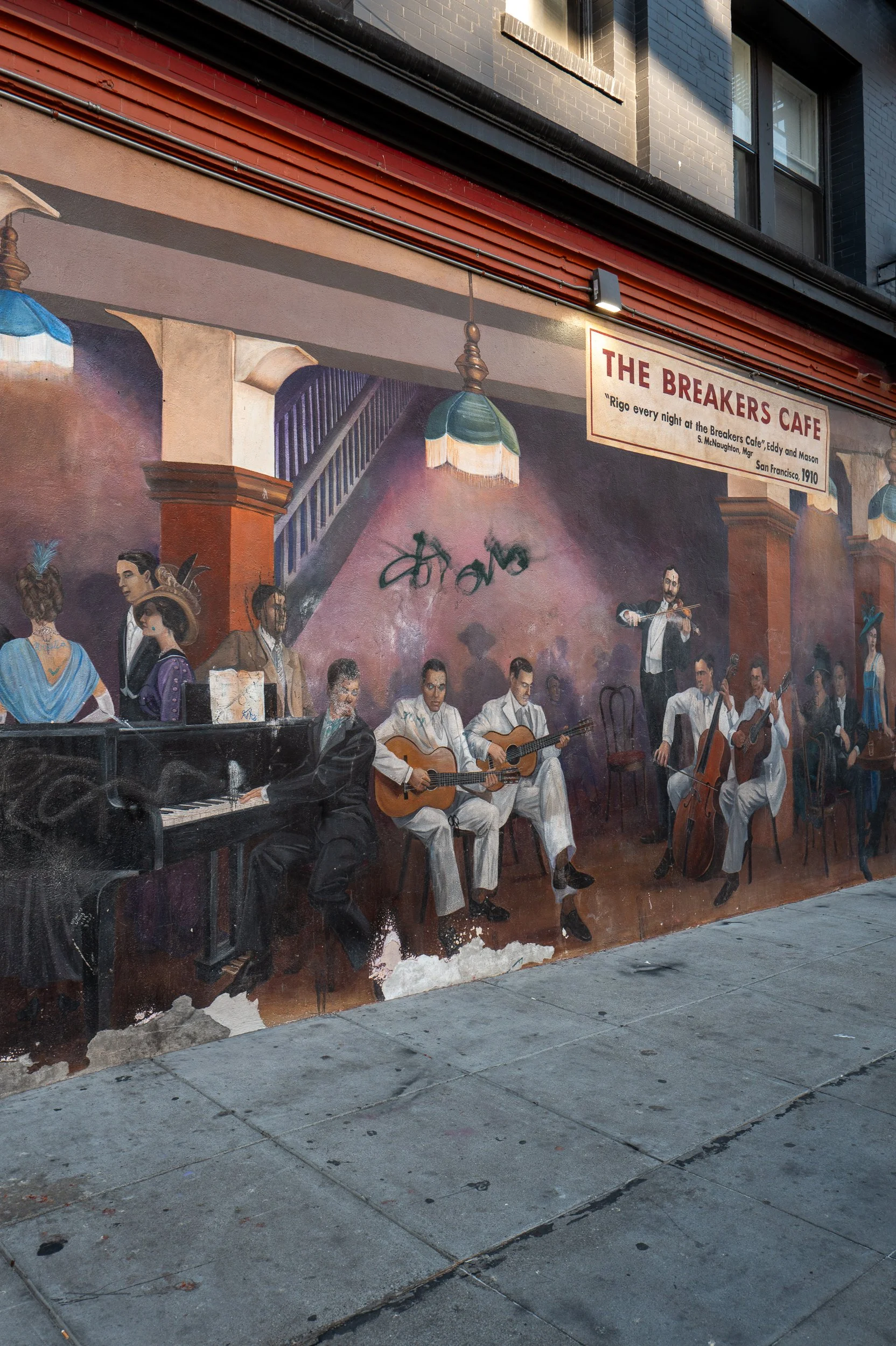 Peinture murale représentant un groupe de musiciens jouant de diverses instruments dans un café historique, avec une scène évoquant la musique et la culture, et un panneau indiquant le nom du lieu : The Breakers Cafe.