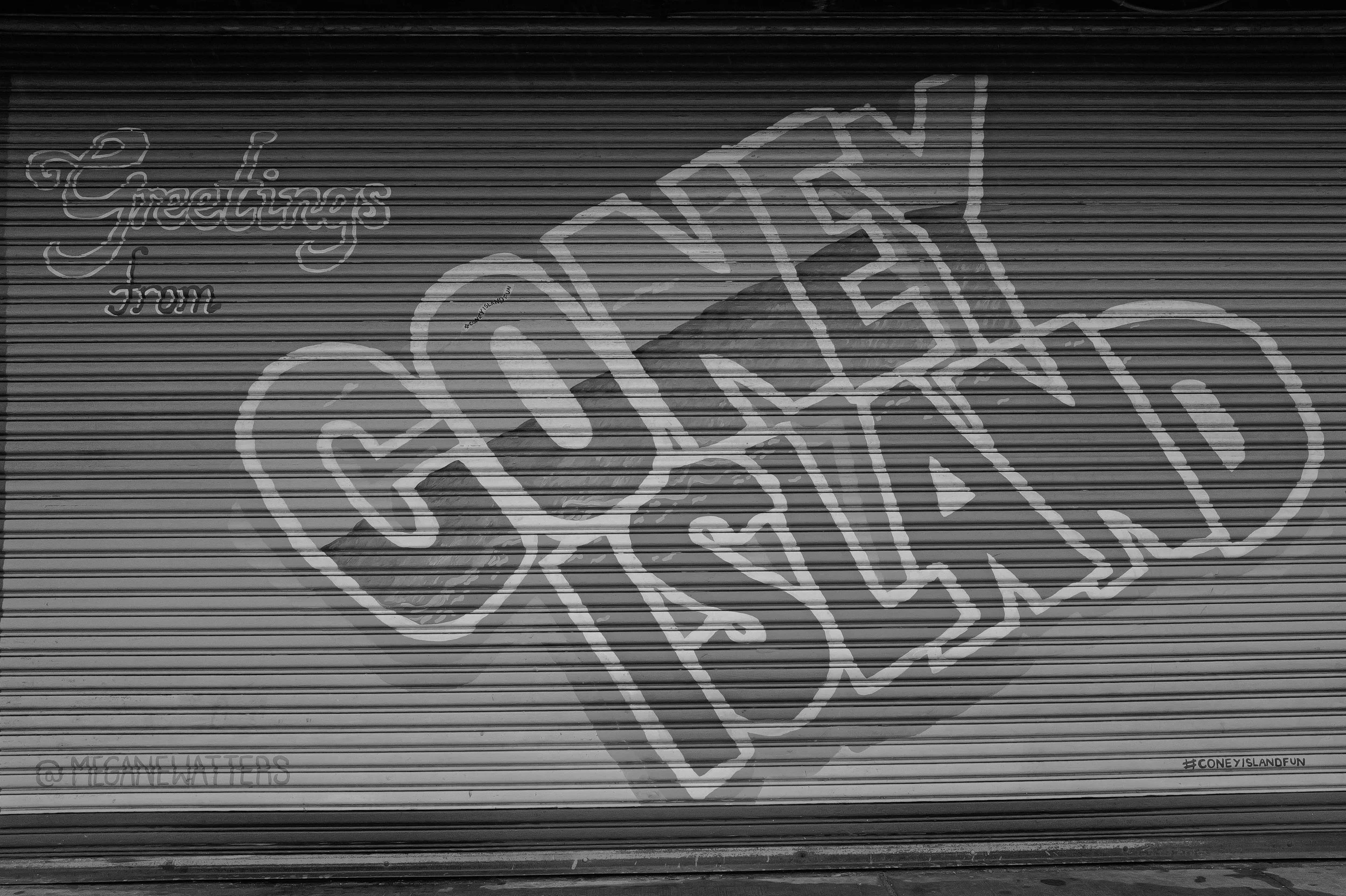 Graffiti sur un rideau métallique avec le message 'Thank you' et le mot 'Coney' écrit en grand, avec un arrière-plan de bâtiment