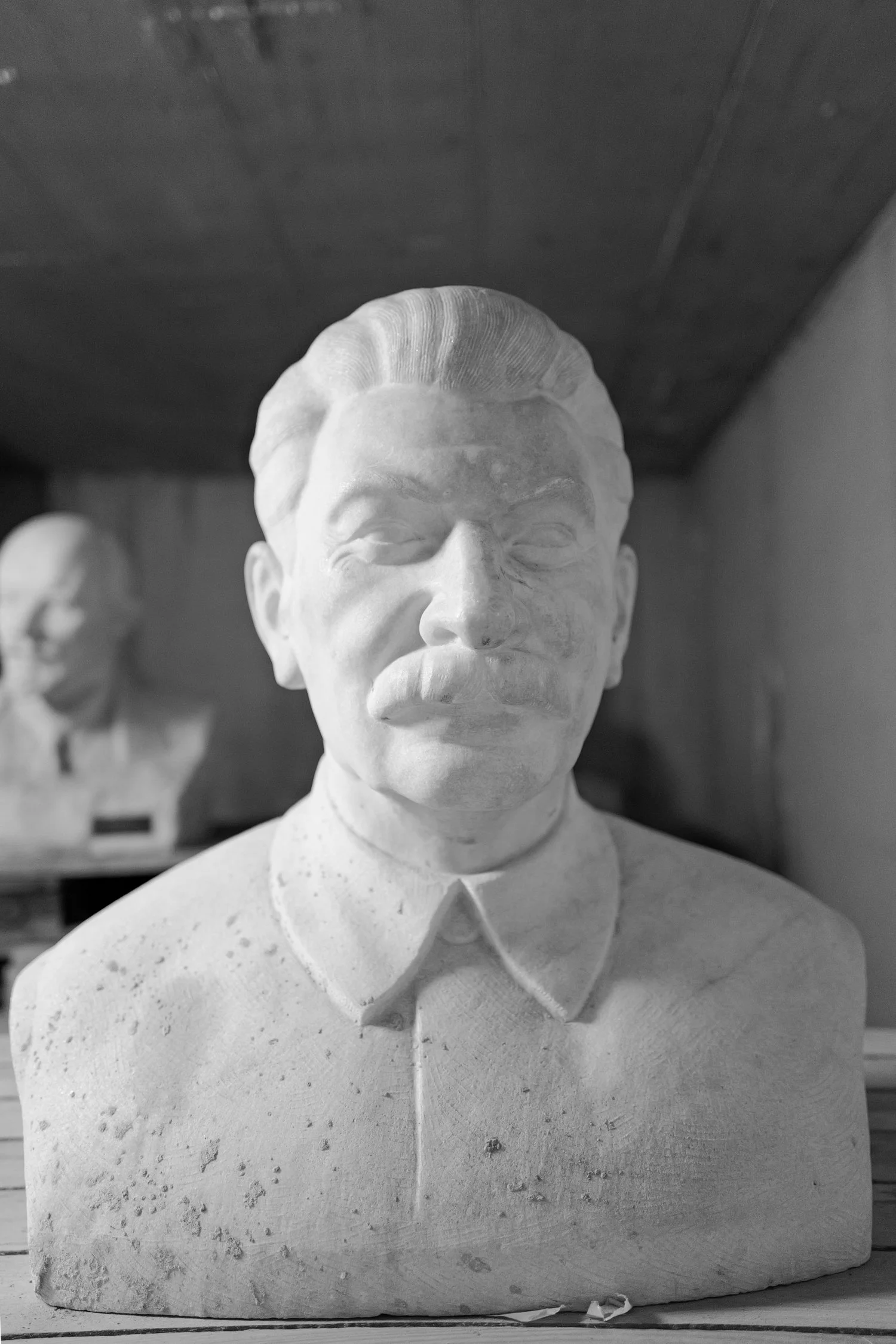 Buste en marbre d'un homme, probablement un leader historique, avec une expression sérieuse, portant une chemise et une veste.