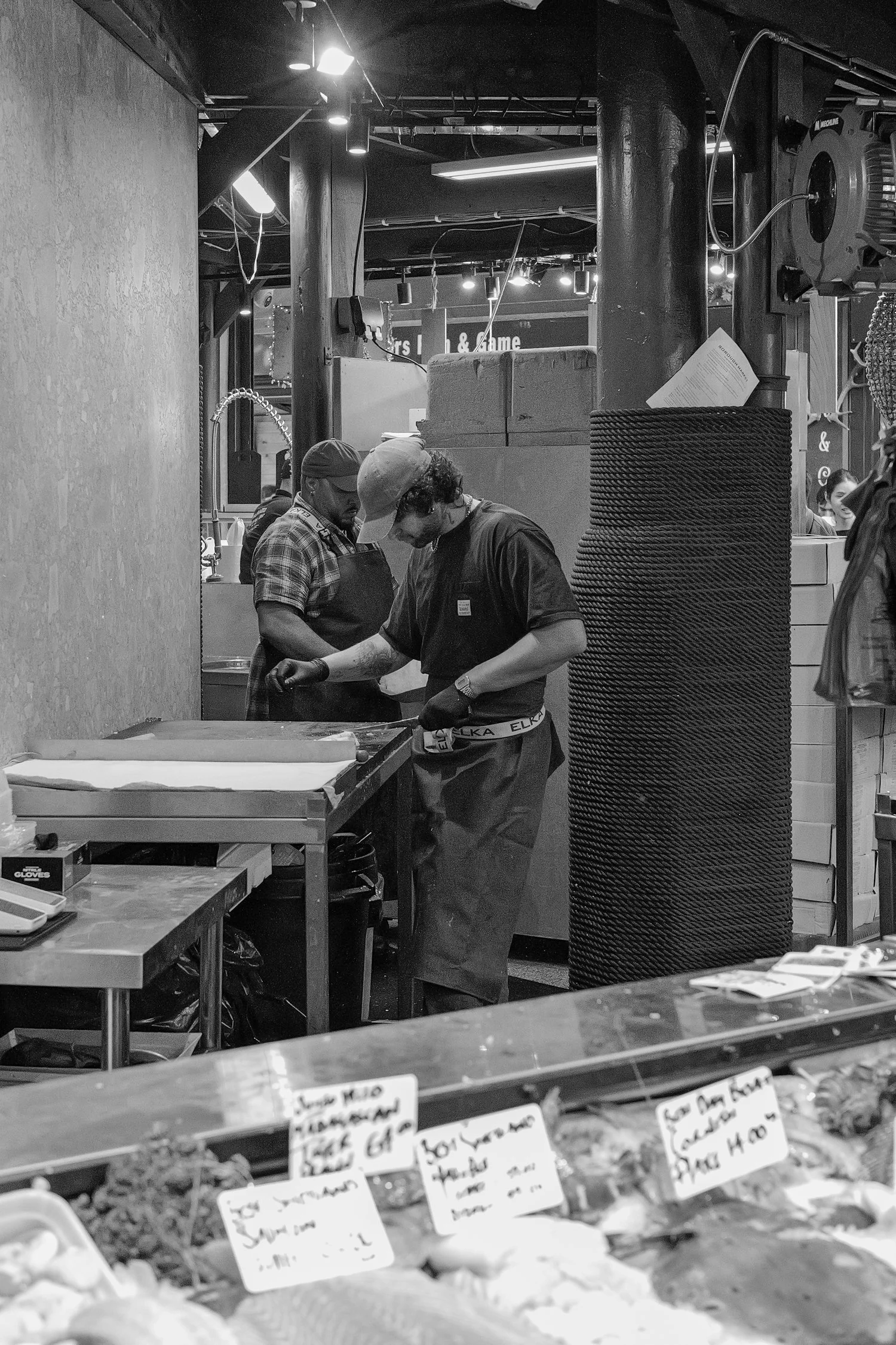 Deux personnes travaillant derrière un comptoir de nourriture dans un restaurant ou une épicerie.