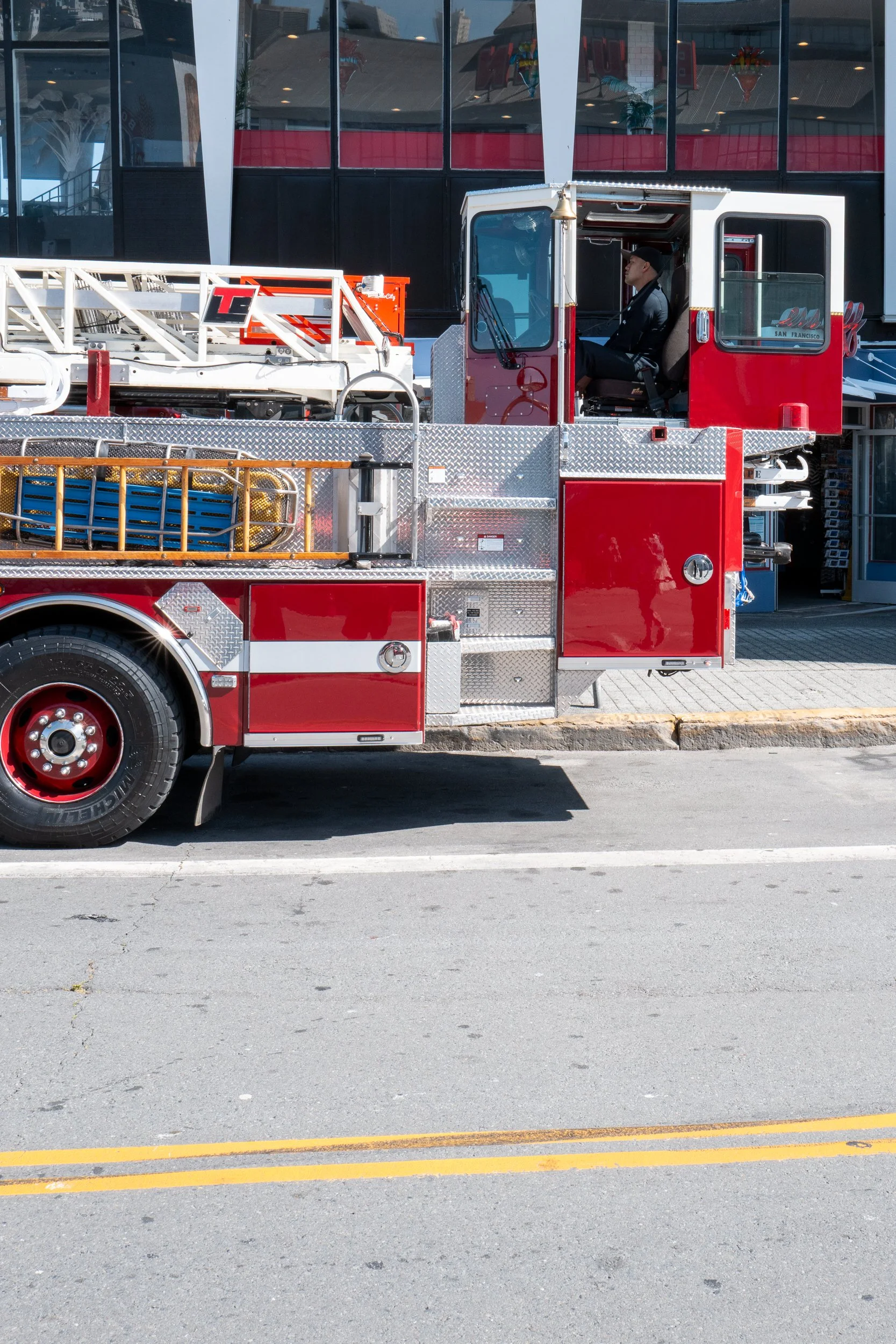 Un camion de pompier rouge stationné en ville, avec un conducteur à l'intérieur.