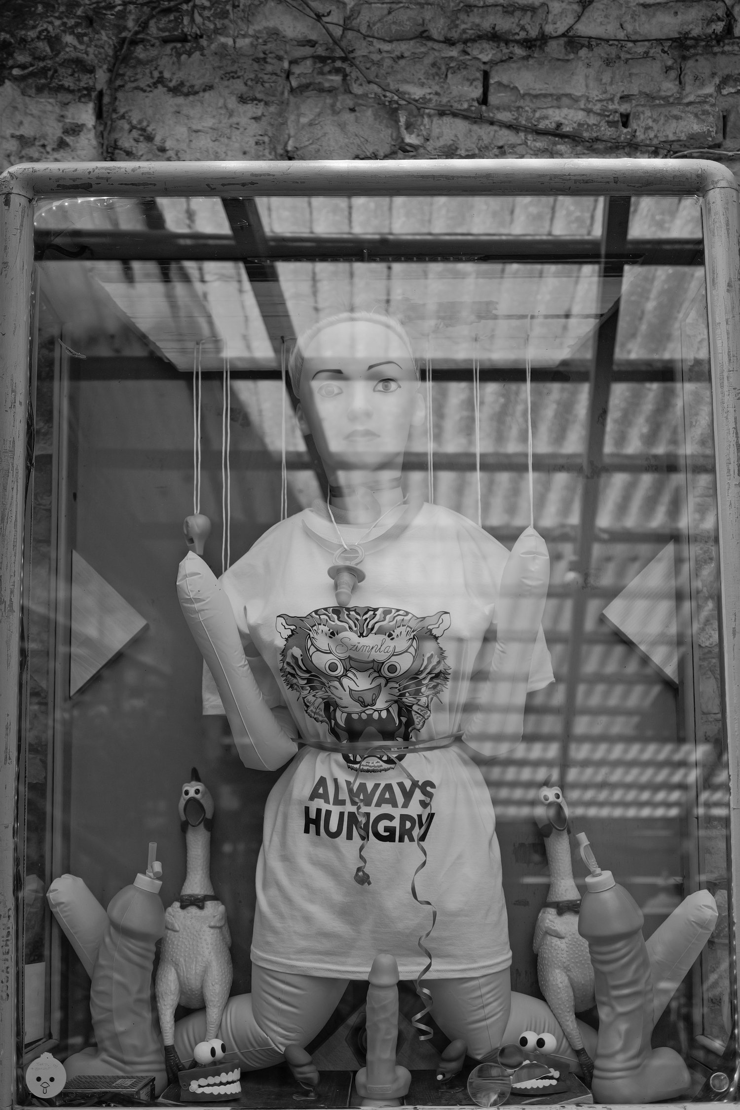 jeune mannequin dans une vitrine, portant un t-shirt avec un tigre, entouré de poupées en peluche, de ballons et de decorations