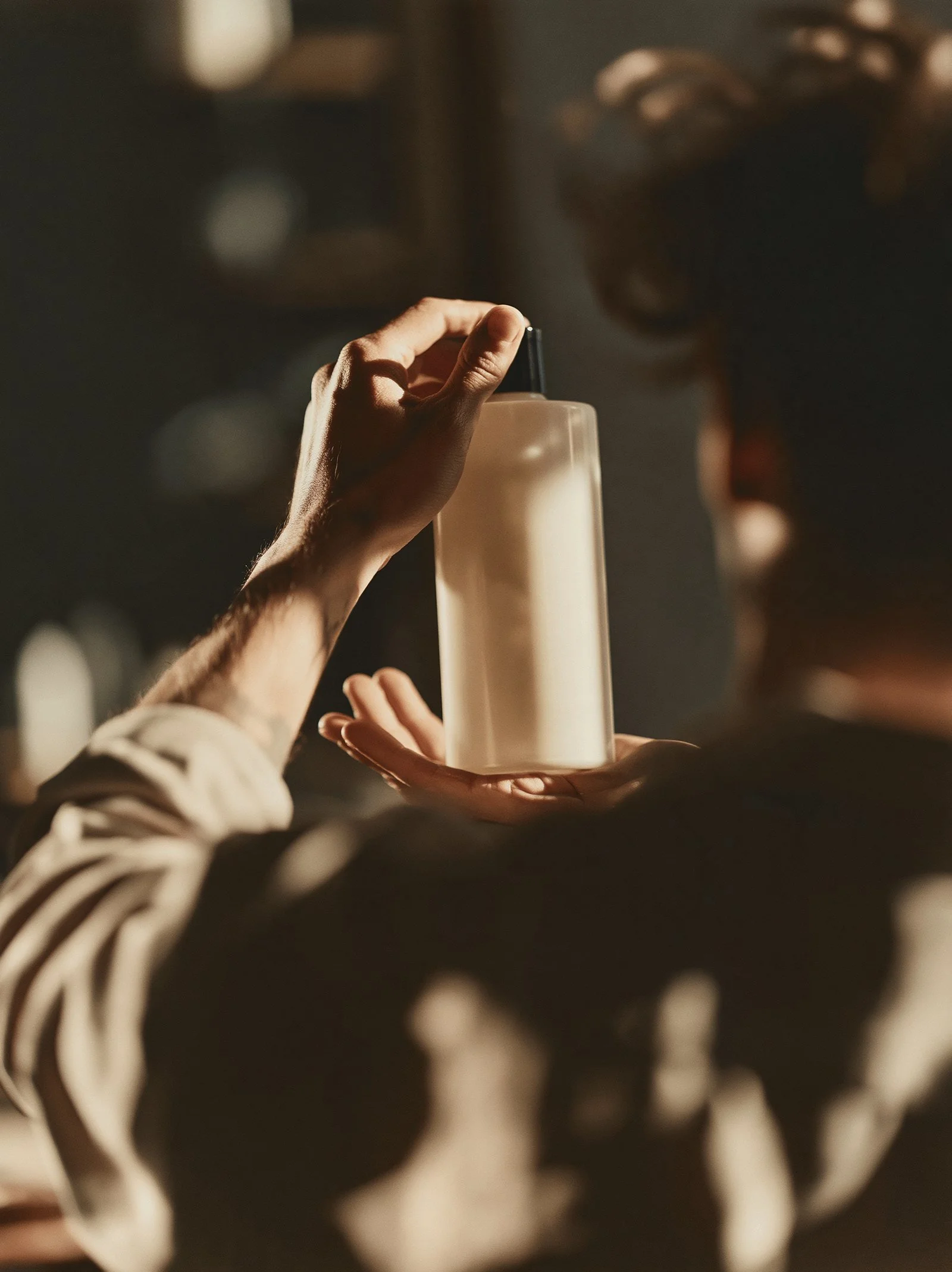 A stylist holding a haircare bottle up to the light in a salon.