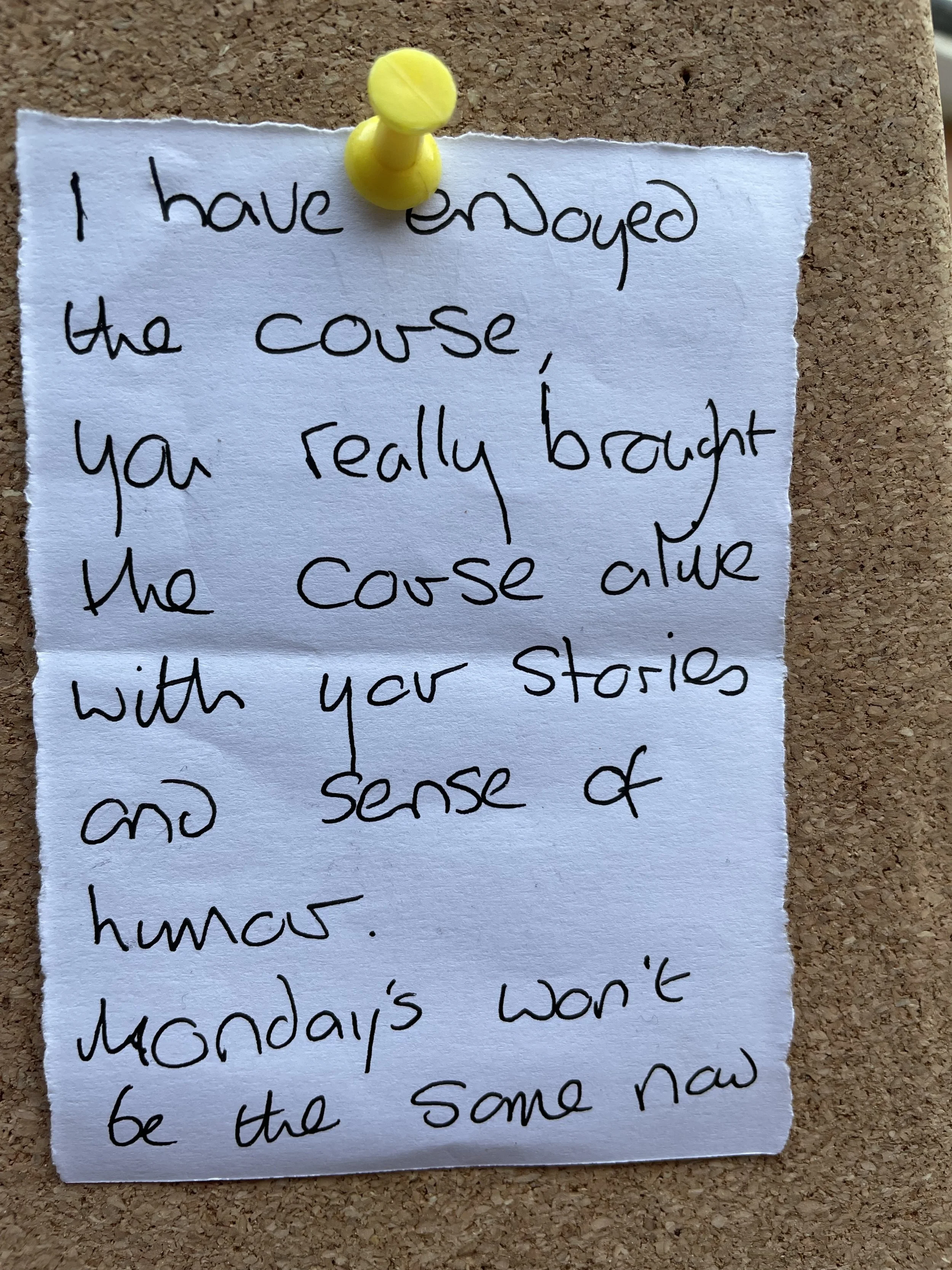 Handwritten note on a piece of torn paper pinned with a yellow pushpin on a corkboard. The note reads, 'I have enjoyed the course, you really brought the course alive with your stories and sense of humor. Monday's won't be the same now.'