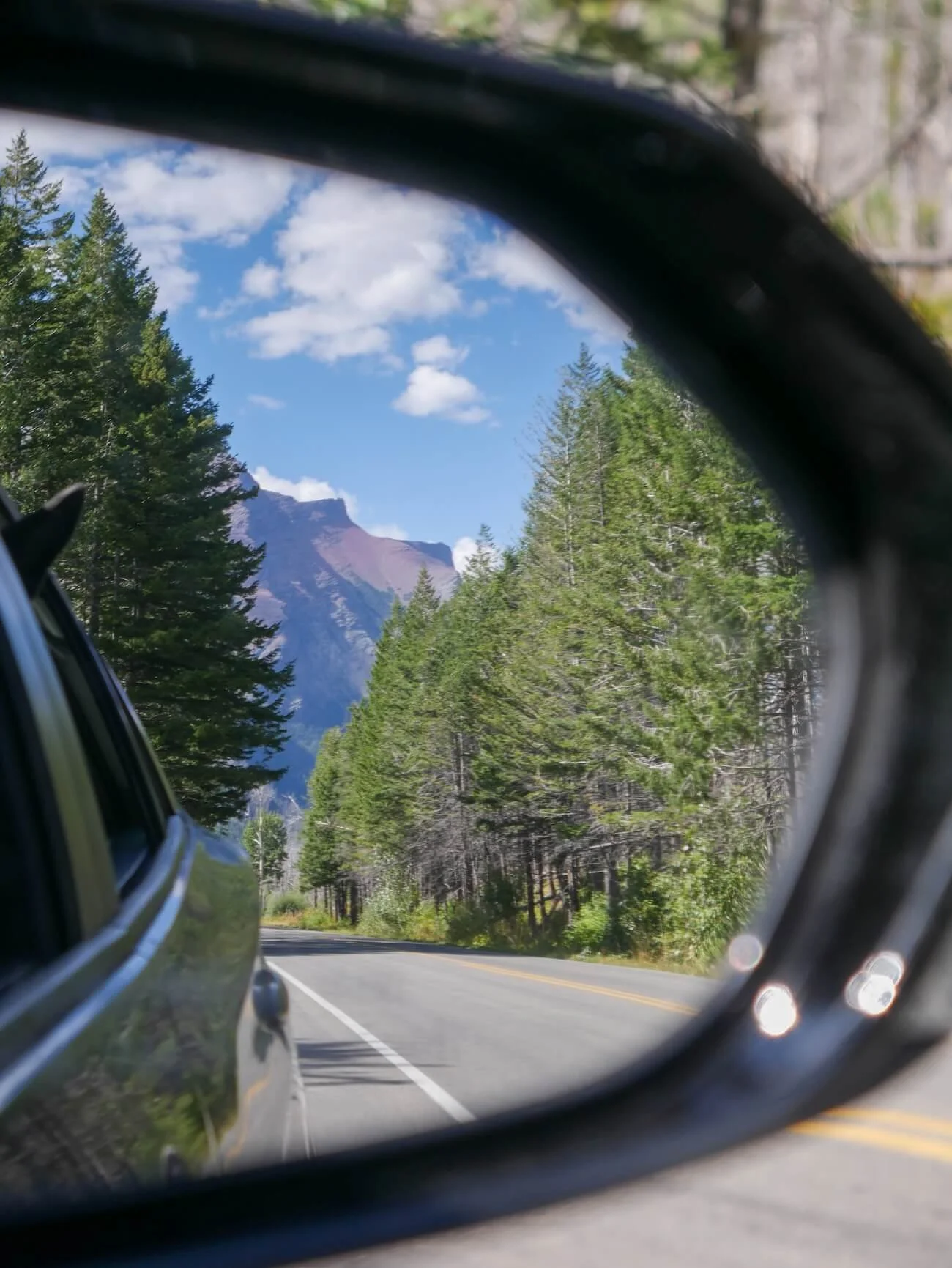mountainous road focused in a car's rear-view mirror