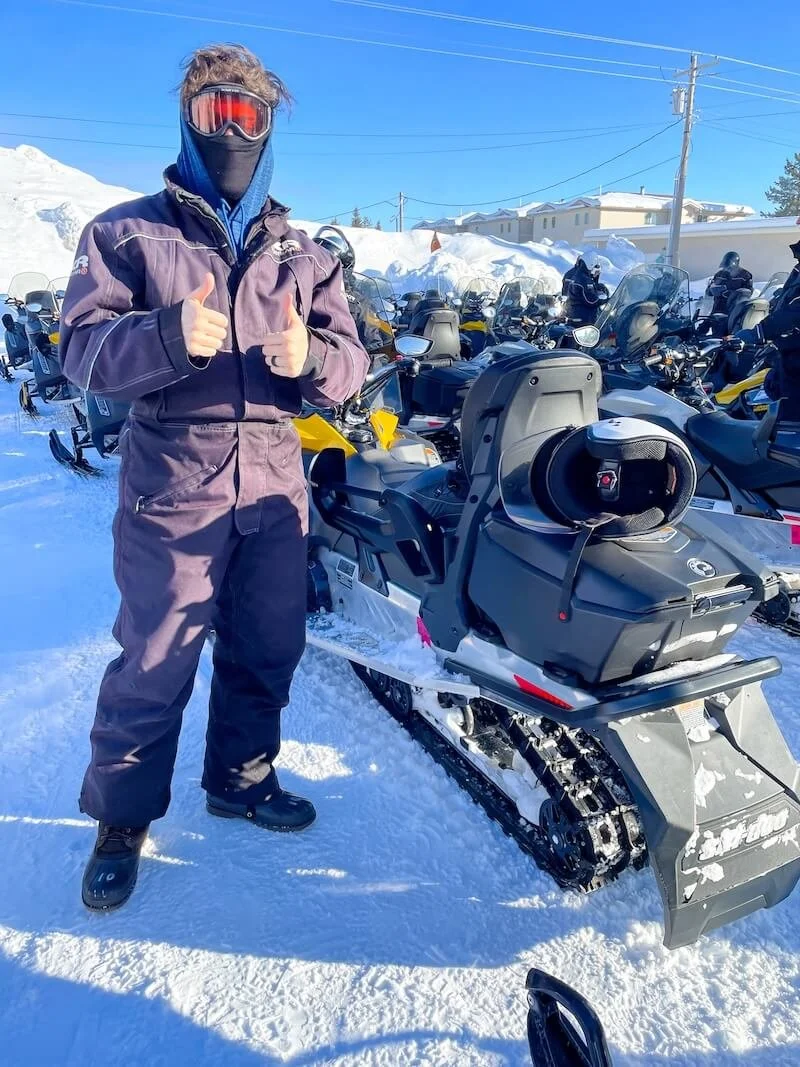 man standing next to snowmobile in town of West Yellowstone