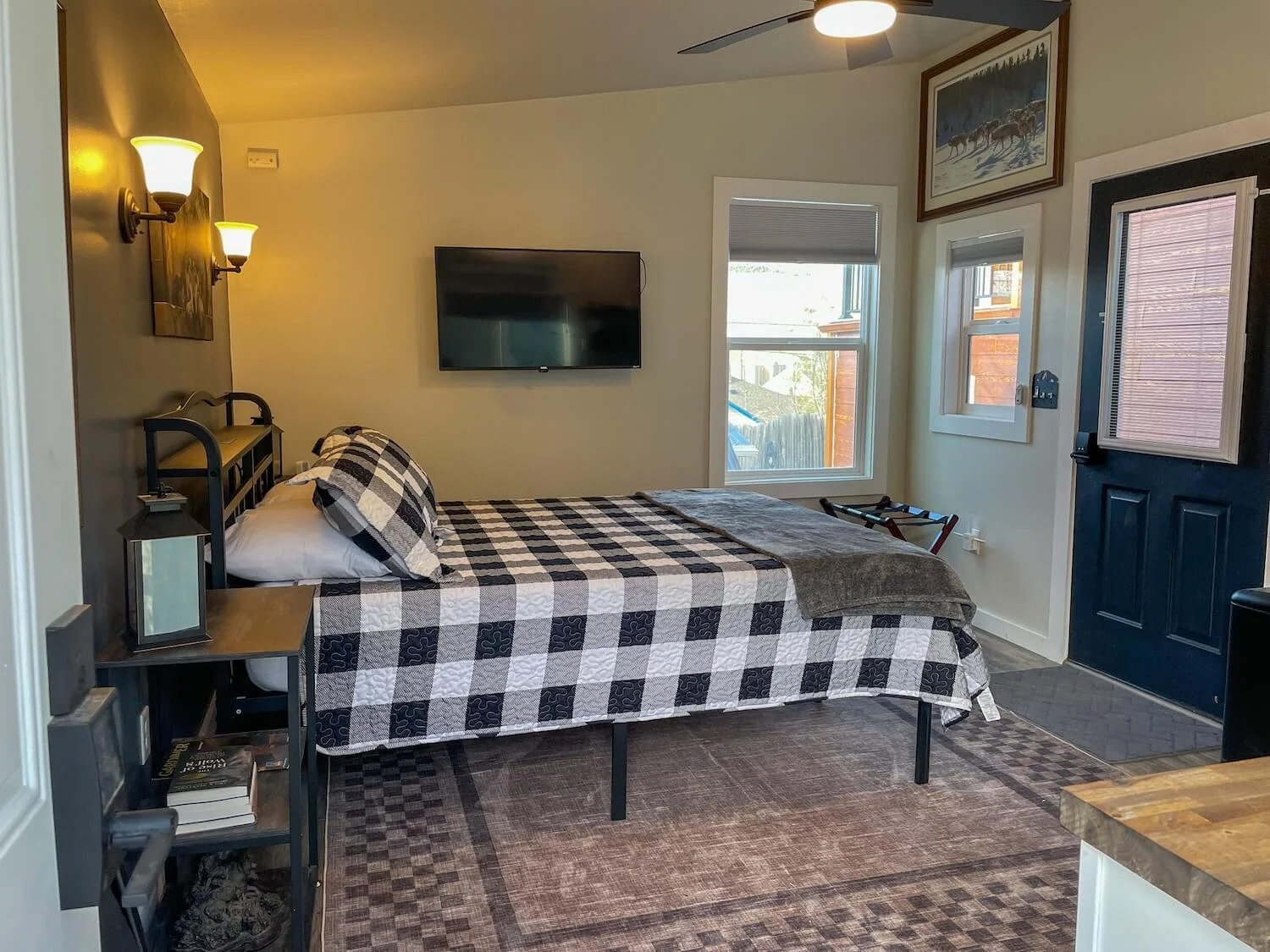 A bedroom with a bed covered in a black and white checkered quilt and matching pillow