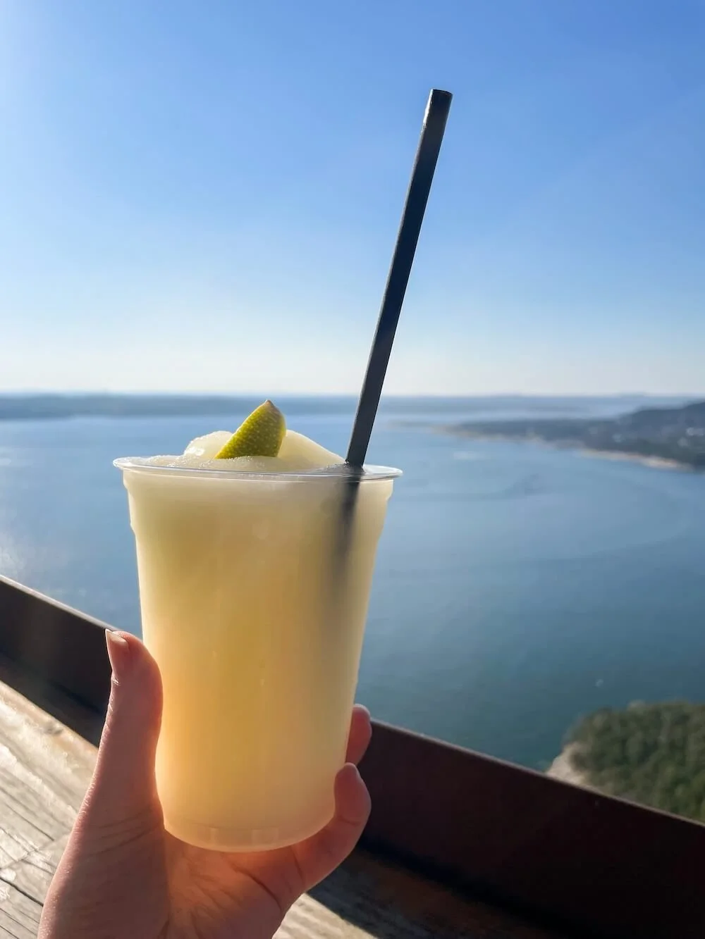 woman holding frozen drink in front of lake view