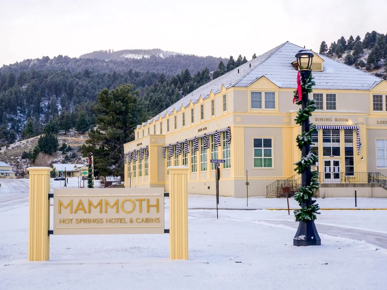 large yellow hotel with Mammoth Hot Springs Hotel welcome sign
