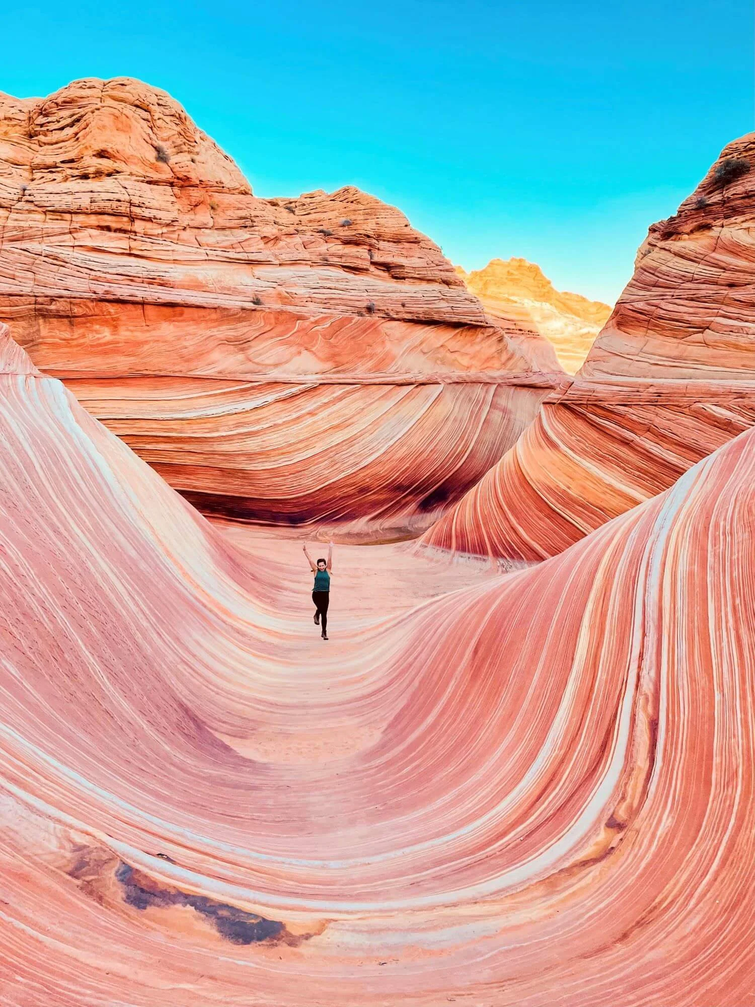 woman celebrating at wave-like sandstone rock formation