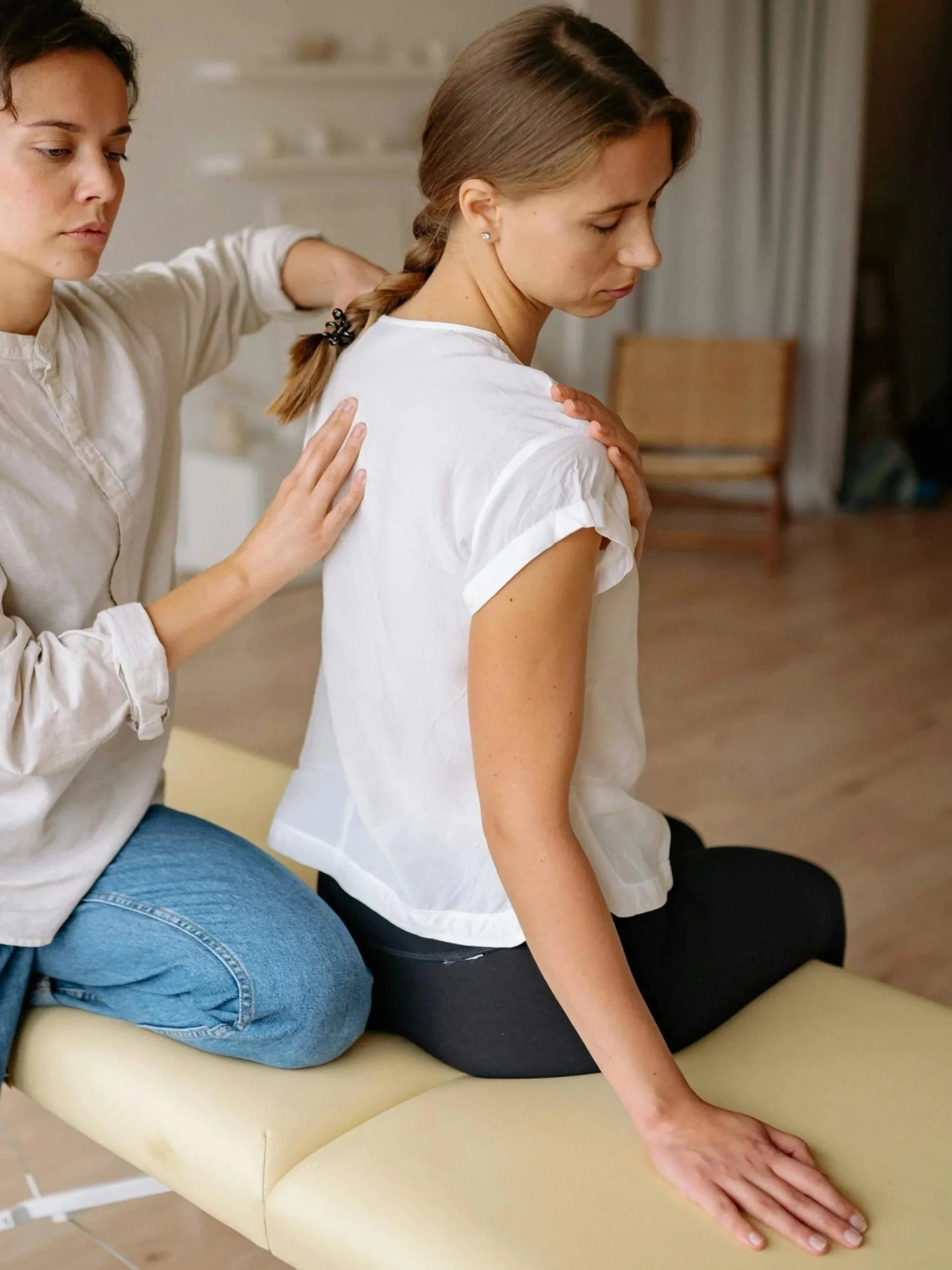 A woman receiving a back massage from another woman in a therapy room.