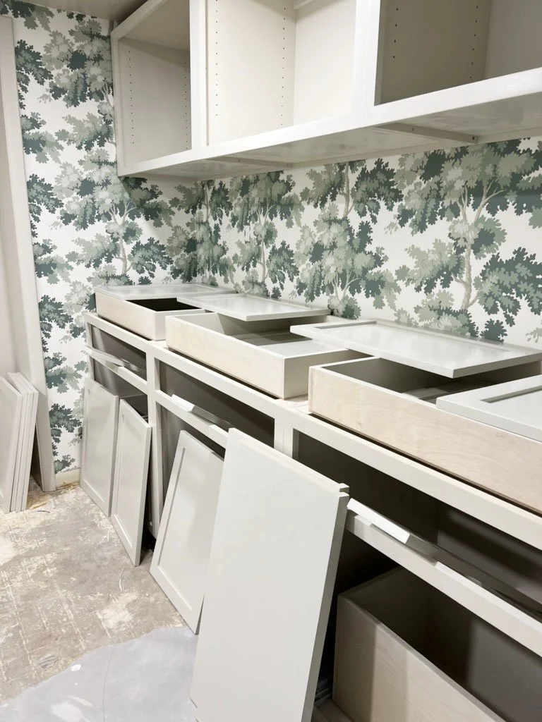  instaling cabinet and green leaf wallpaper for laundry room makeover 