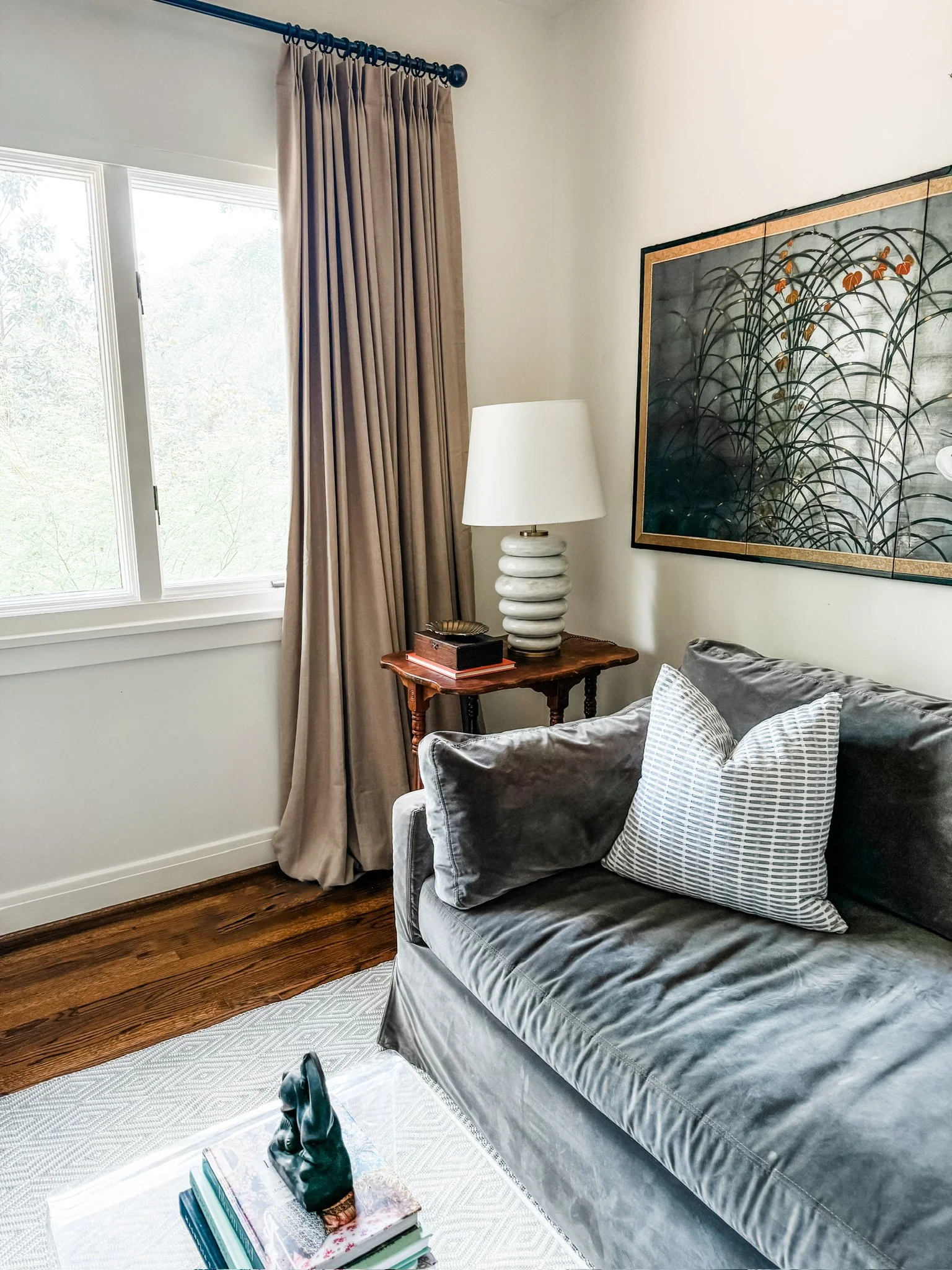 Living room with taupe velvet curtains, a grey velvet sofa and framed art