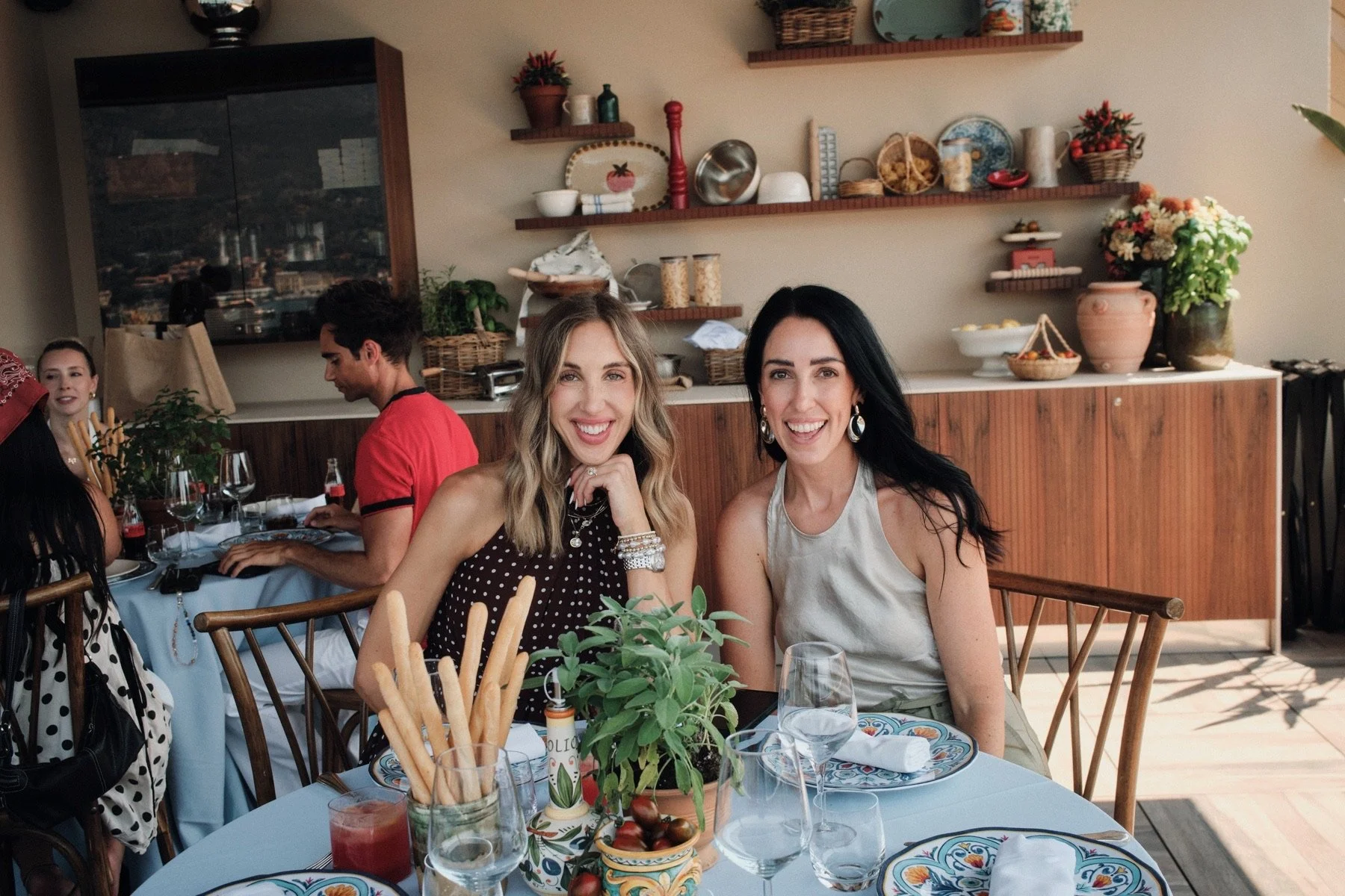 Friends gathered around a restaurant table with drinks and breadsticks in Italy