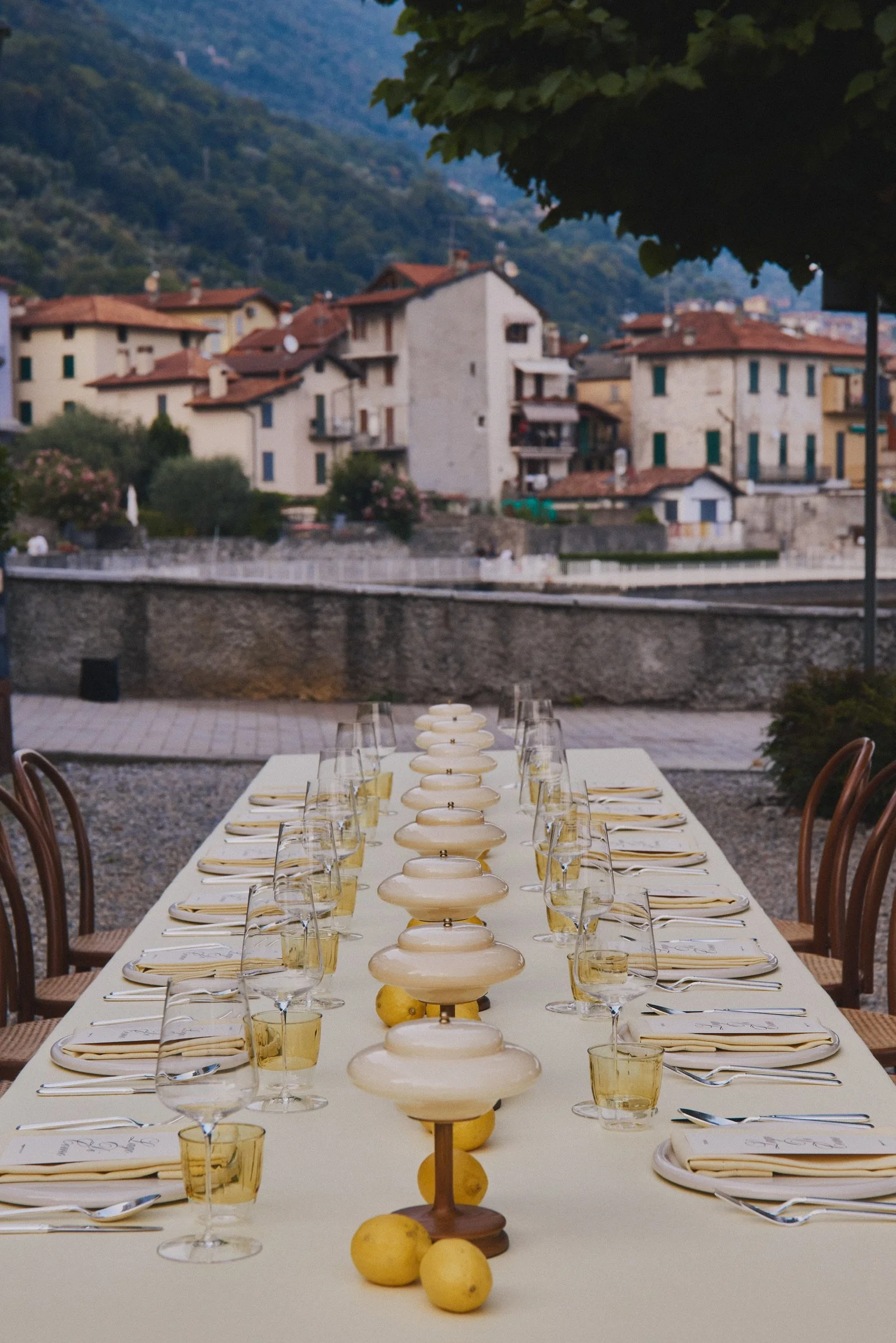 Long outdoor dinner table set with lemons and glassware in an Italian courtyard