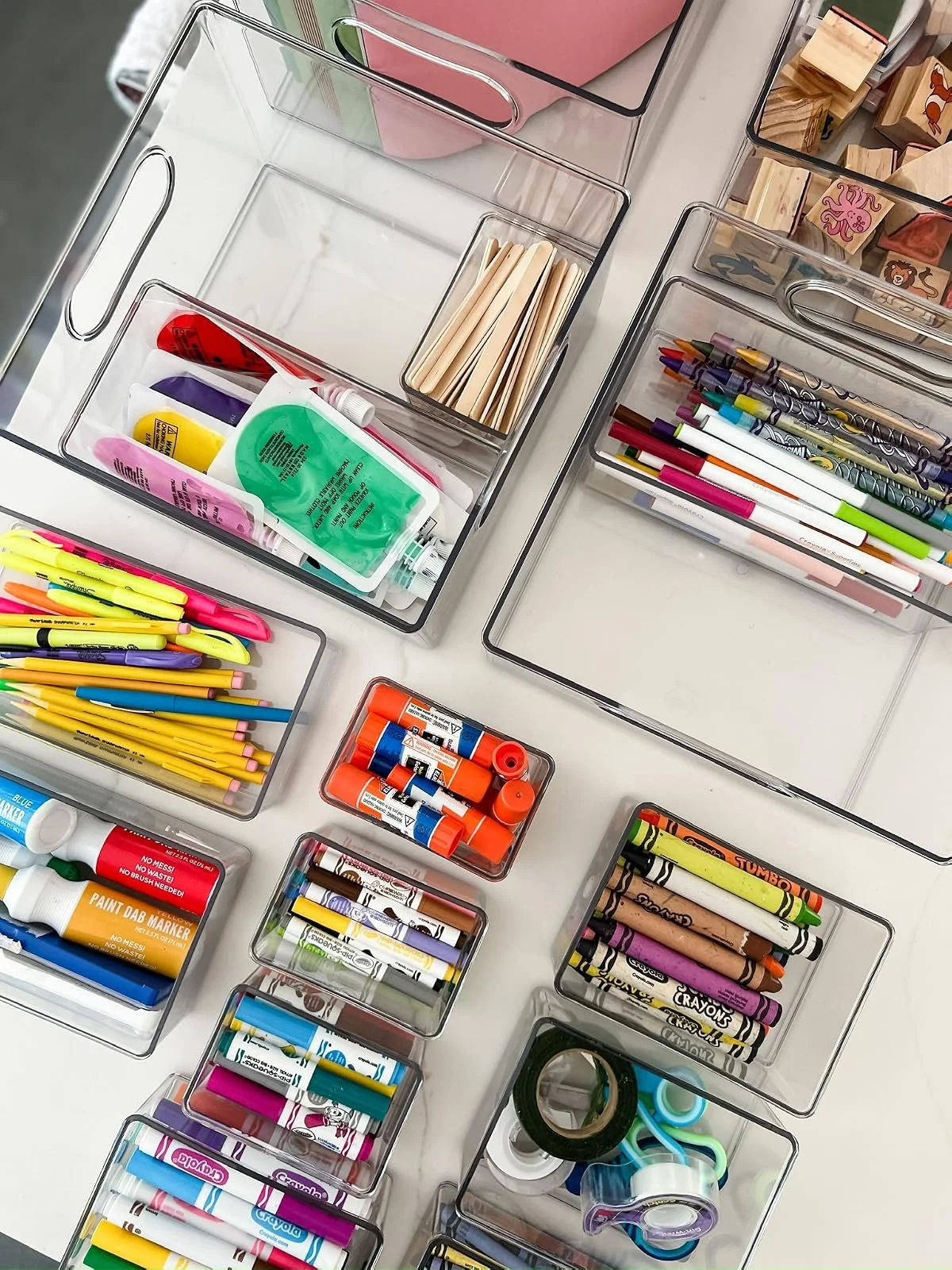 Clear acrylic drawer organizers holding pens, markers, tape and school supplies