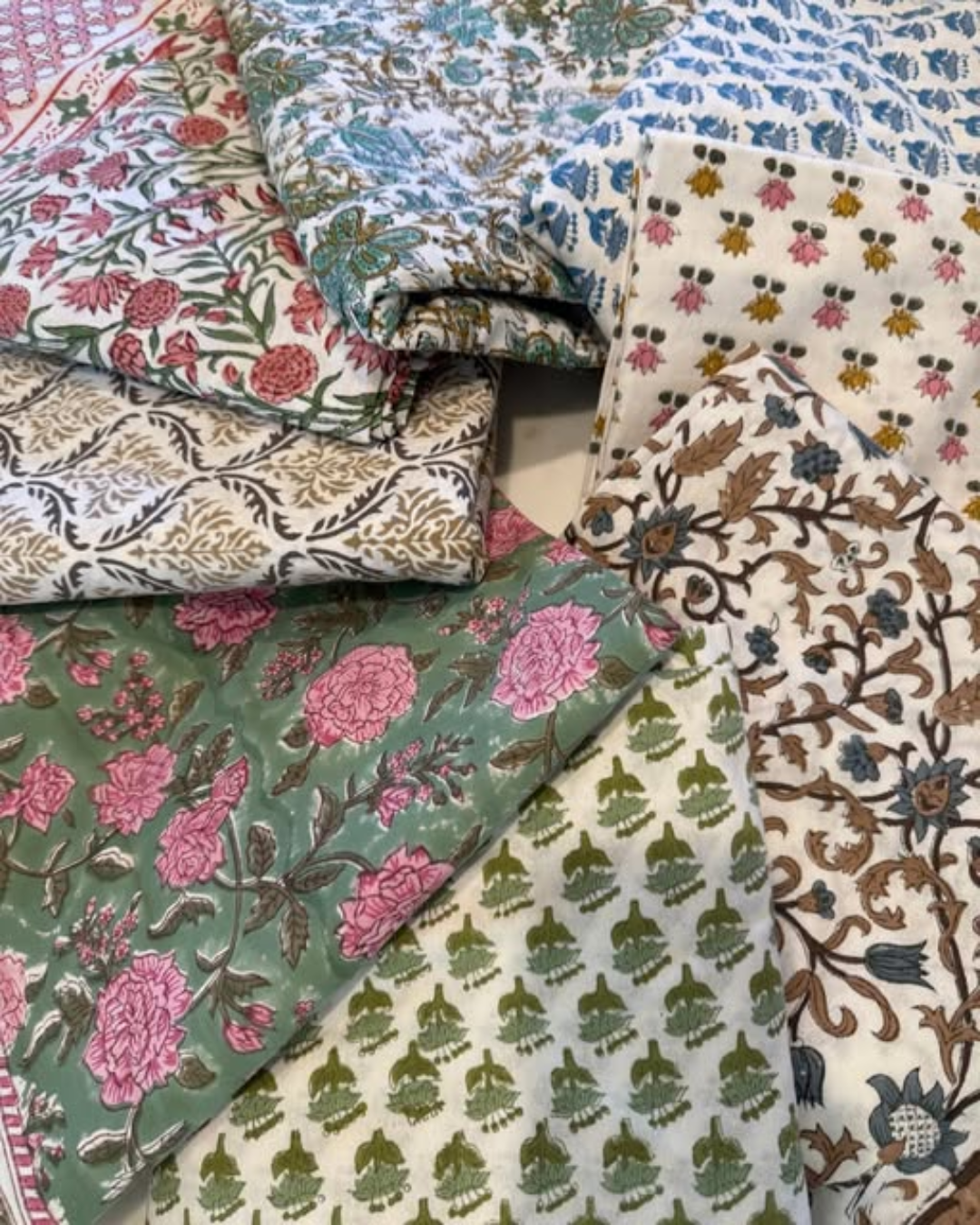 Stack of folded block print fabrics in pink, green and blue florals