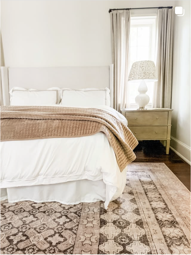 Neutral bedroom with white bedding, a tan throw and a vintage-style rug