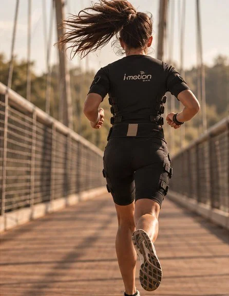 Femme qui court sur une passerelle en combinaison EMS, reprise du sport