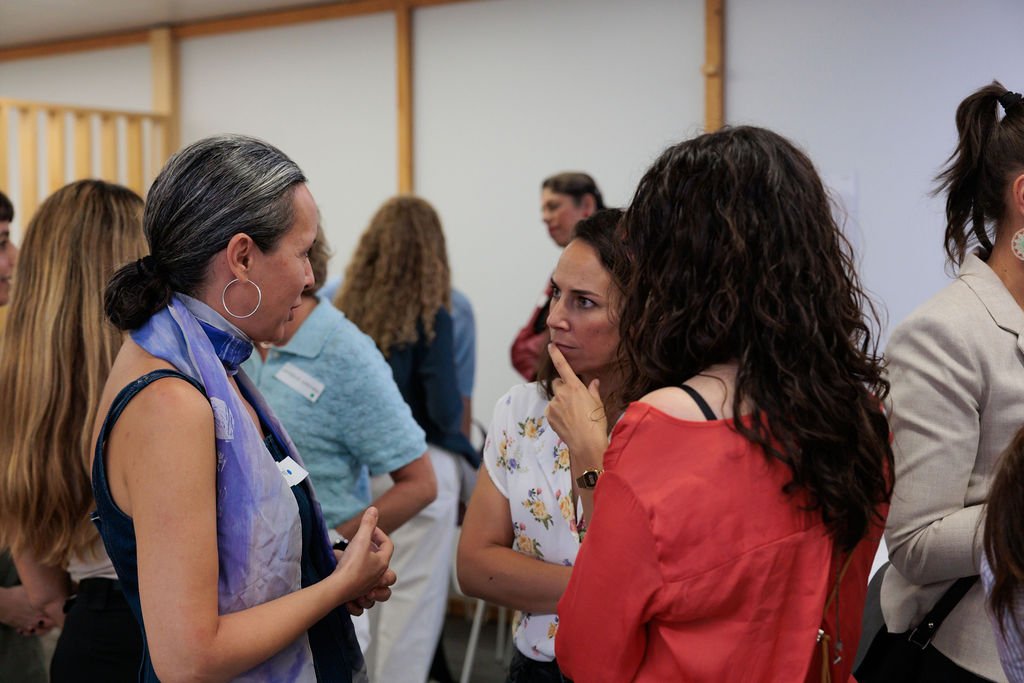 Varias asistentes conversan de pie durante el networking del encuentro