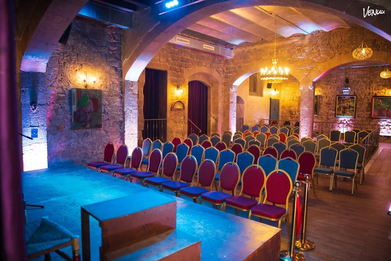 Salón Barroco de Palau Dalmases, espacio histórico con paredes de piedra e iluminación cálida en Barcelona.
