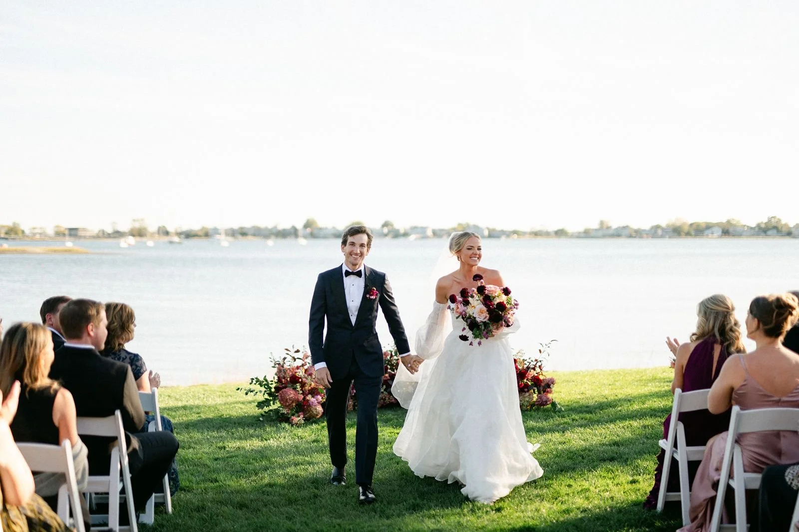 Bride and groom standing behind a waterfront backdrop