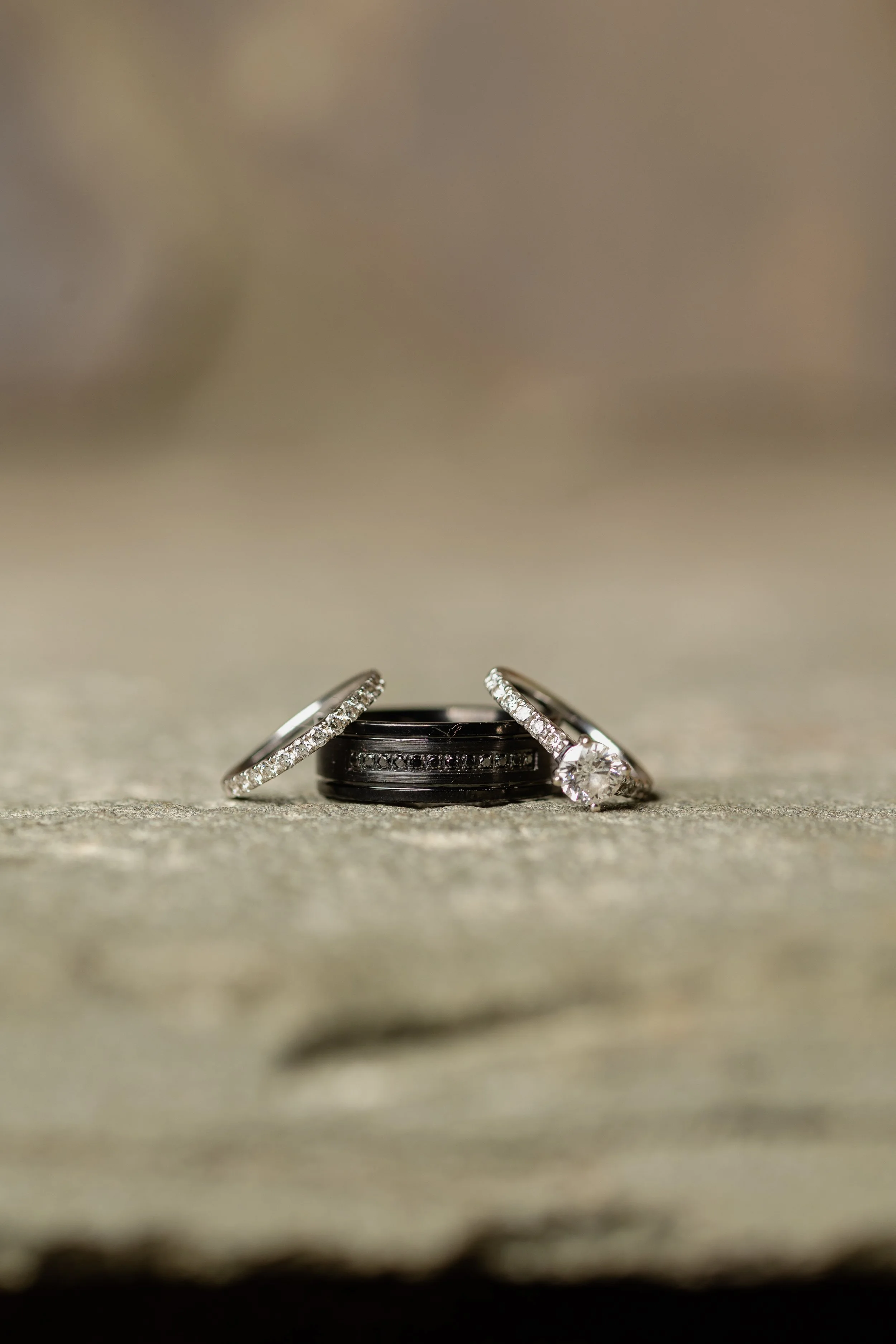 Three rings, including one with a large diamond, arranged on a textured surface for a flat lay photo.