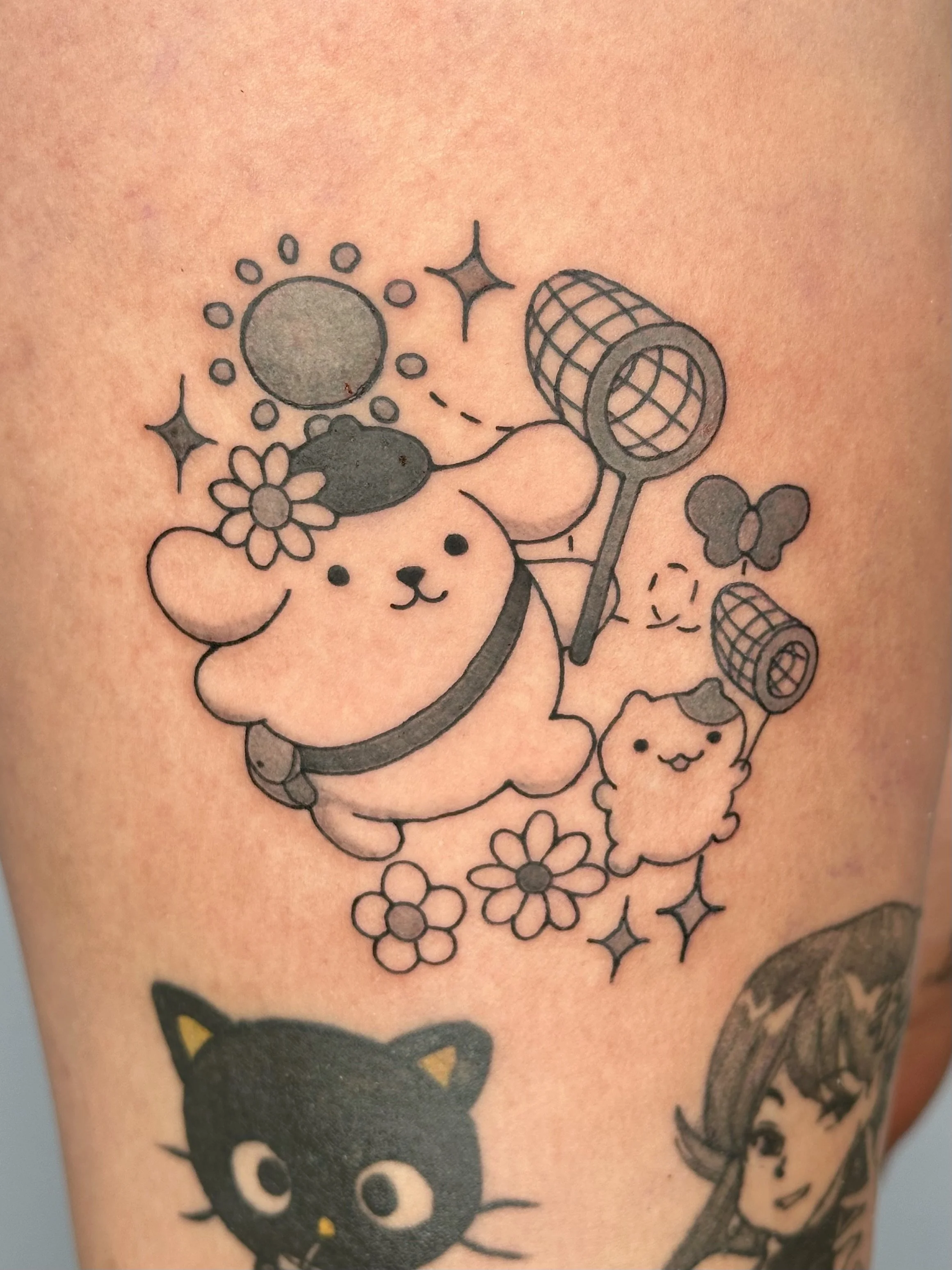 Tattoo of a cute bear with a flower on its head, surrounded by flowers, sparkles, and holding a butterfly net, accompanied by a smaller fluffy bear holding a butterfly net and several smaller decorative elements.