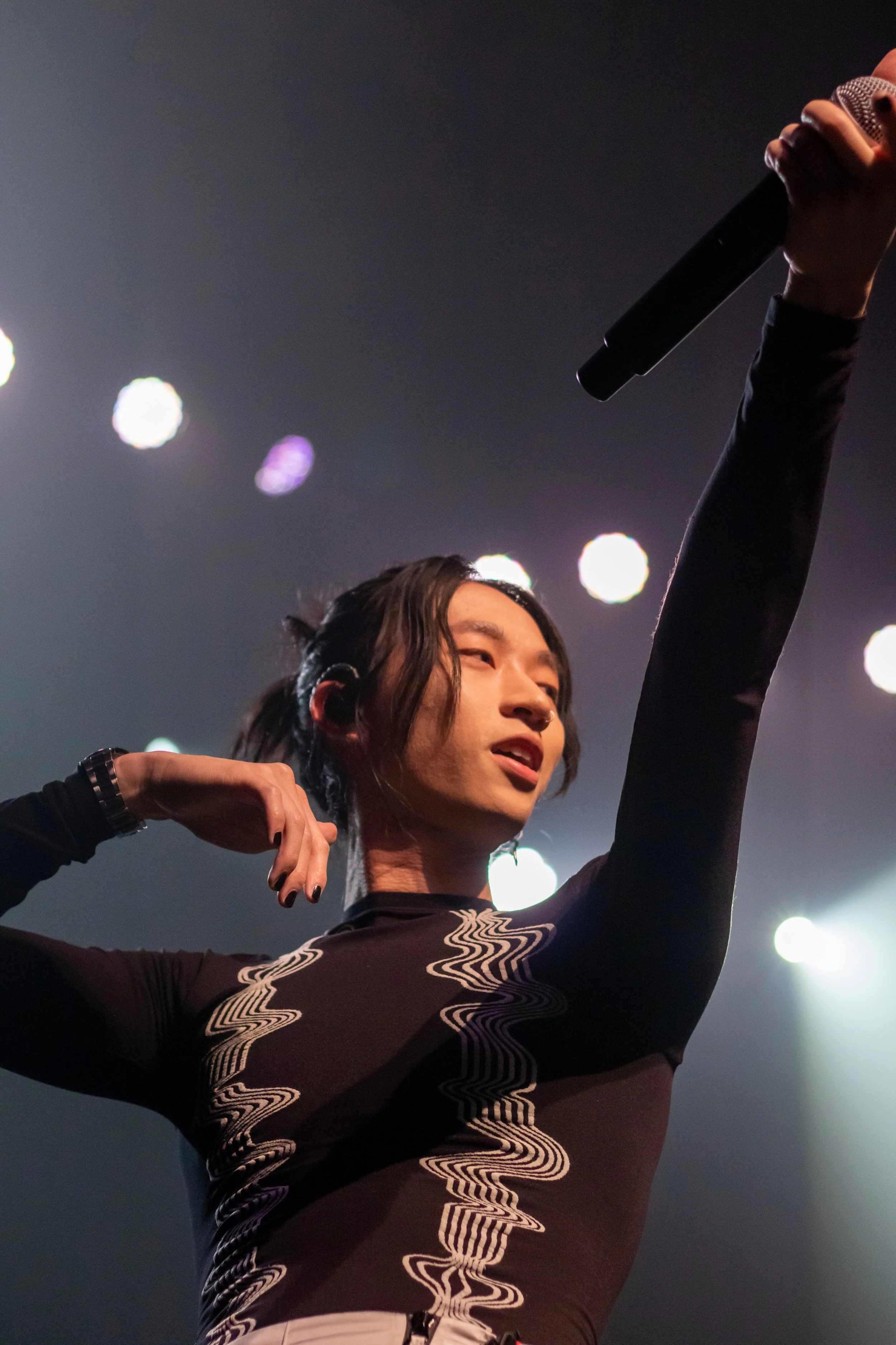 Lo-fi artist keshi performing at the Fonda Theatre in Los Angeles on June 14, 2022 during his HELL/HEAVEN Tour. He's holding the microphone out to the crowd so they can sing. Concert photography by Giannina Fredo.