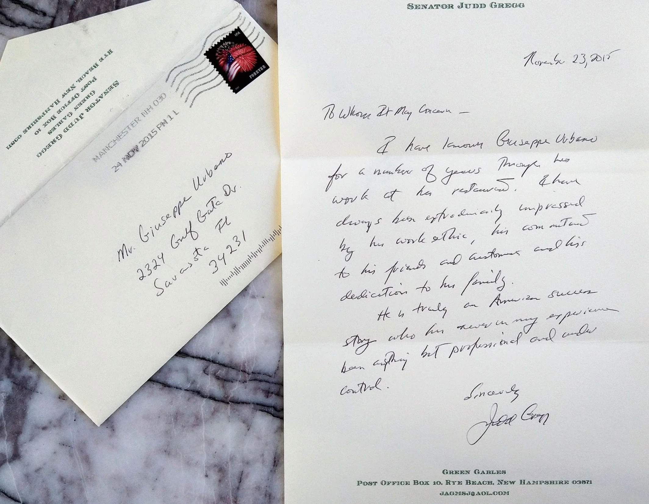 A handwritten letter on white paper, dated November 23, 2015, and an envelope with a red and black postage stamp, both placed on a marble surface.