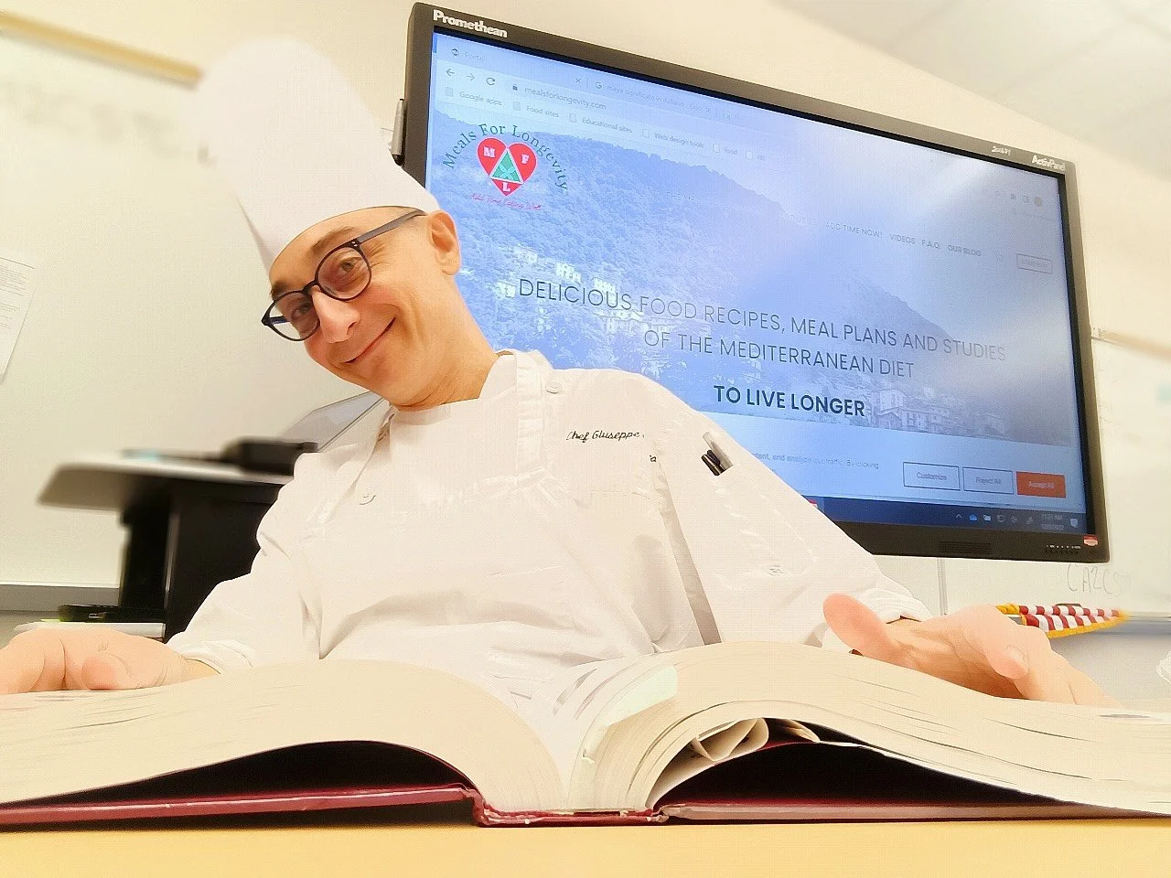 Executive Chef Giuseppe Urbano reviewing Mediterranean Diet research and scientific references supporting the Meals For Longevity Program Framework™