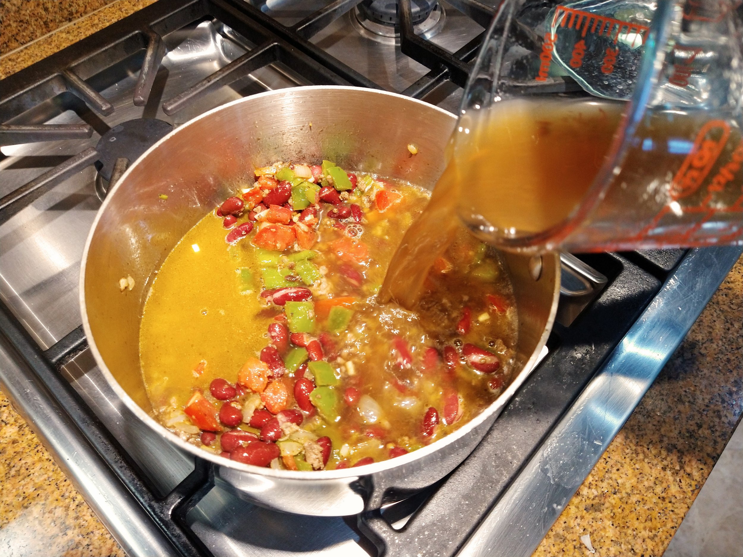 Add broth to Chili con Carne Soup for the Mediterranean Diet recipe