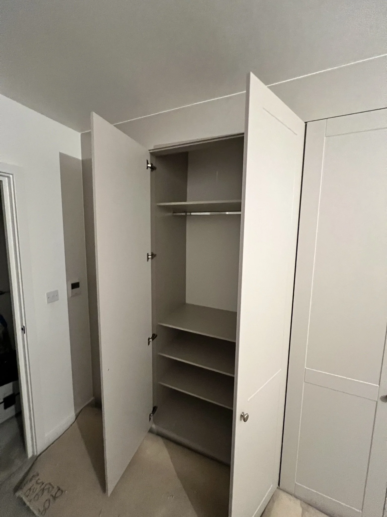 Open white closet with shelves and hanging rod