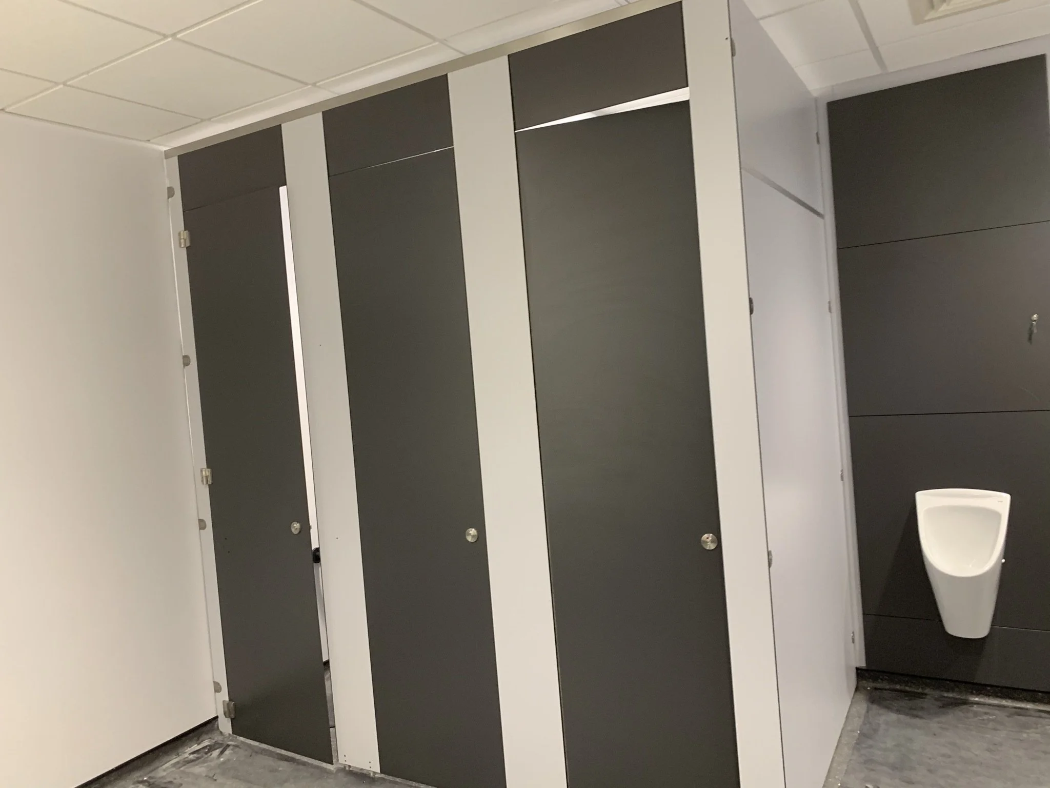 Public restroom with toilet stalls and a wall-mounted urinal.