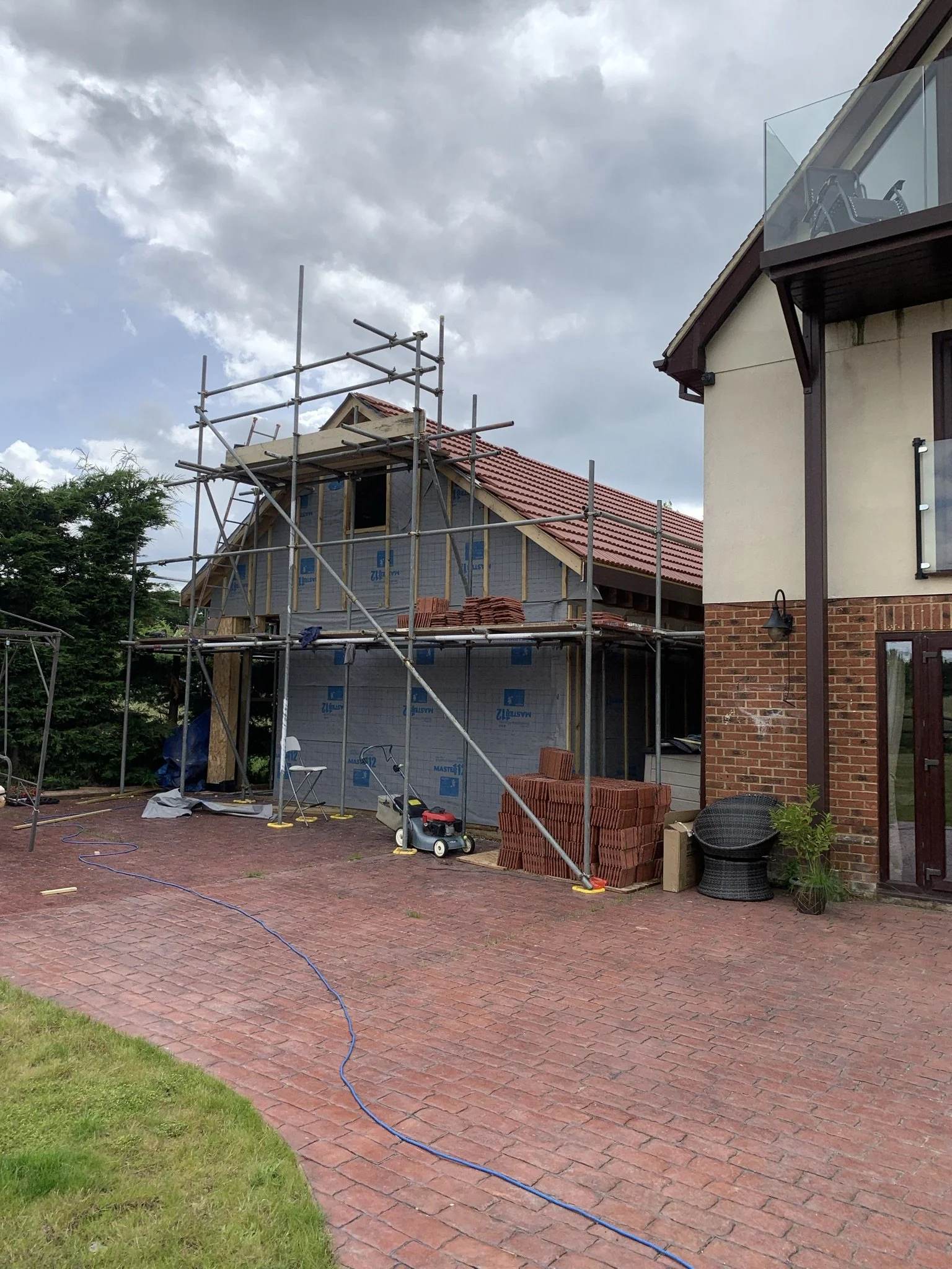 Construction site with a house under renovation, scaffolding, and building materials like bricks and tiles.