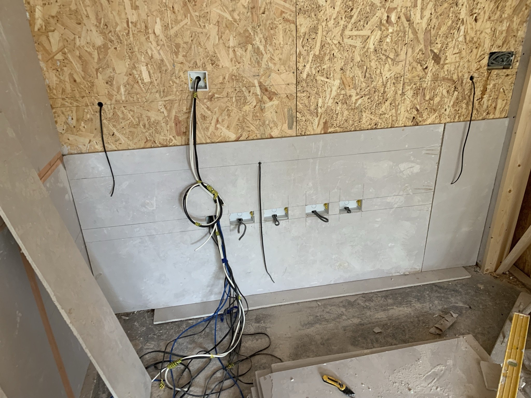 A construction site wall with exposed cables and partially installed electrical outlets.
