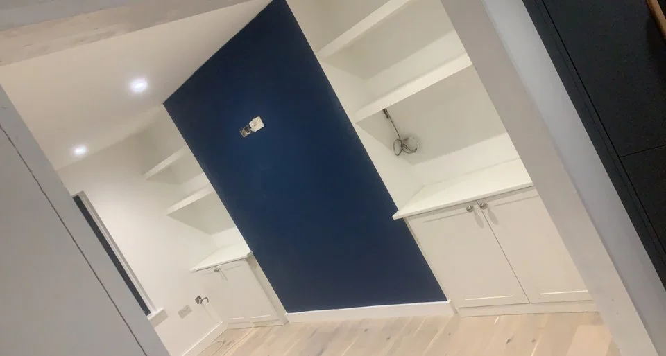 Modern room with white cabinets, blue accent wall, and built-in shelves.