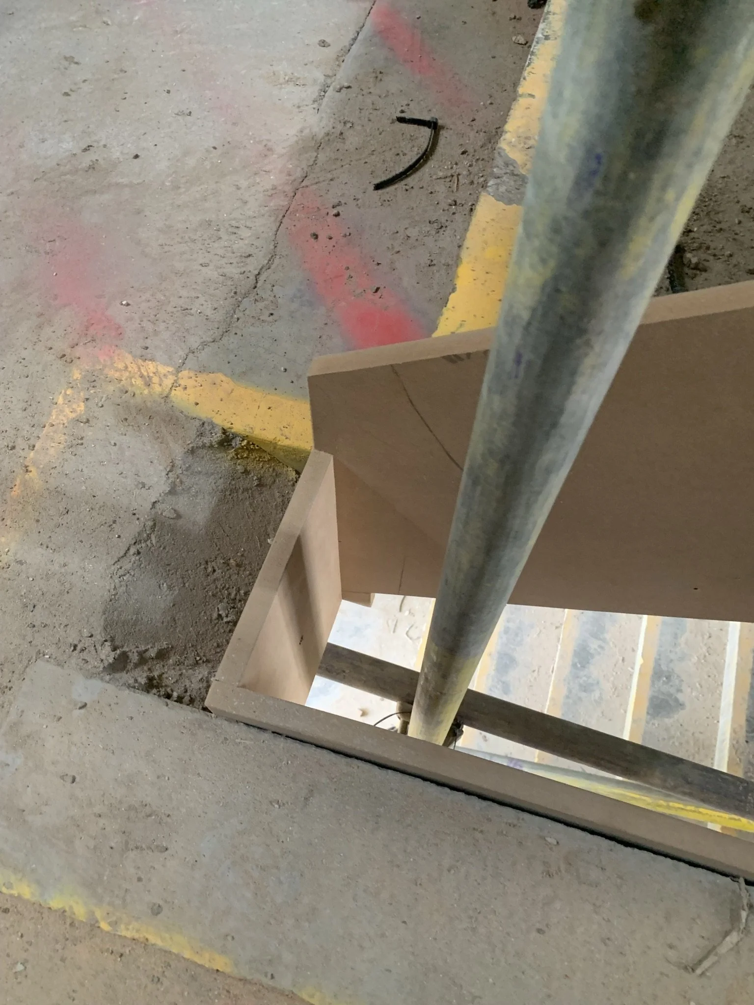 Concrete floor with metal pole, construction markings on ground