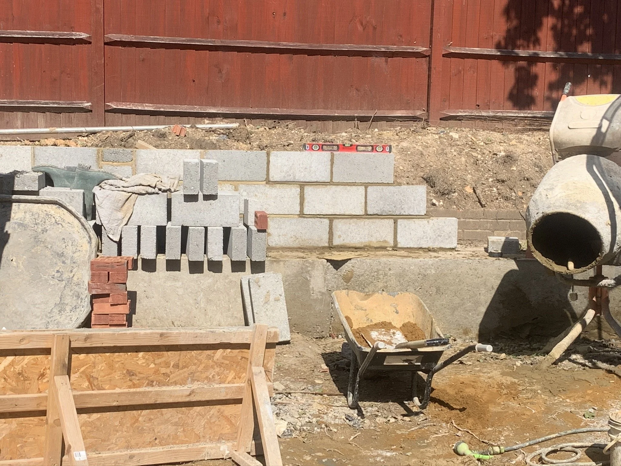 Construction site with concrete blocks, wheelbarrow, and cement mixer.