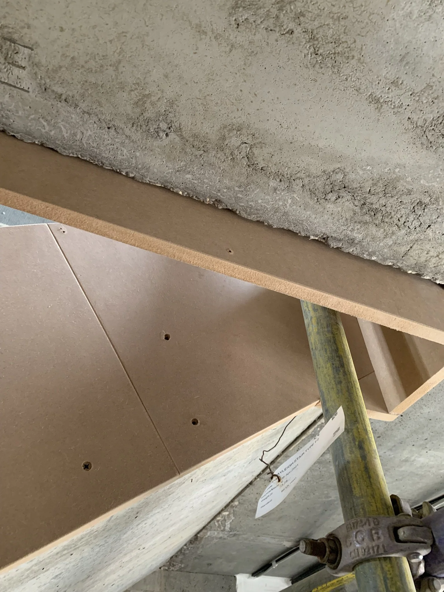 Concrete surface with wooden board, scaffold pole, and clamp