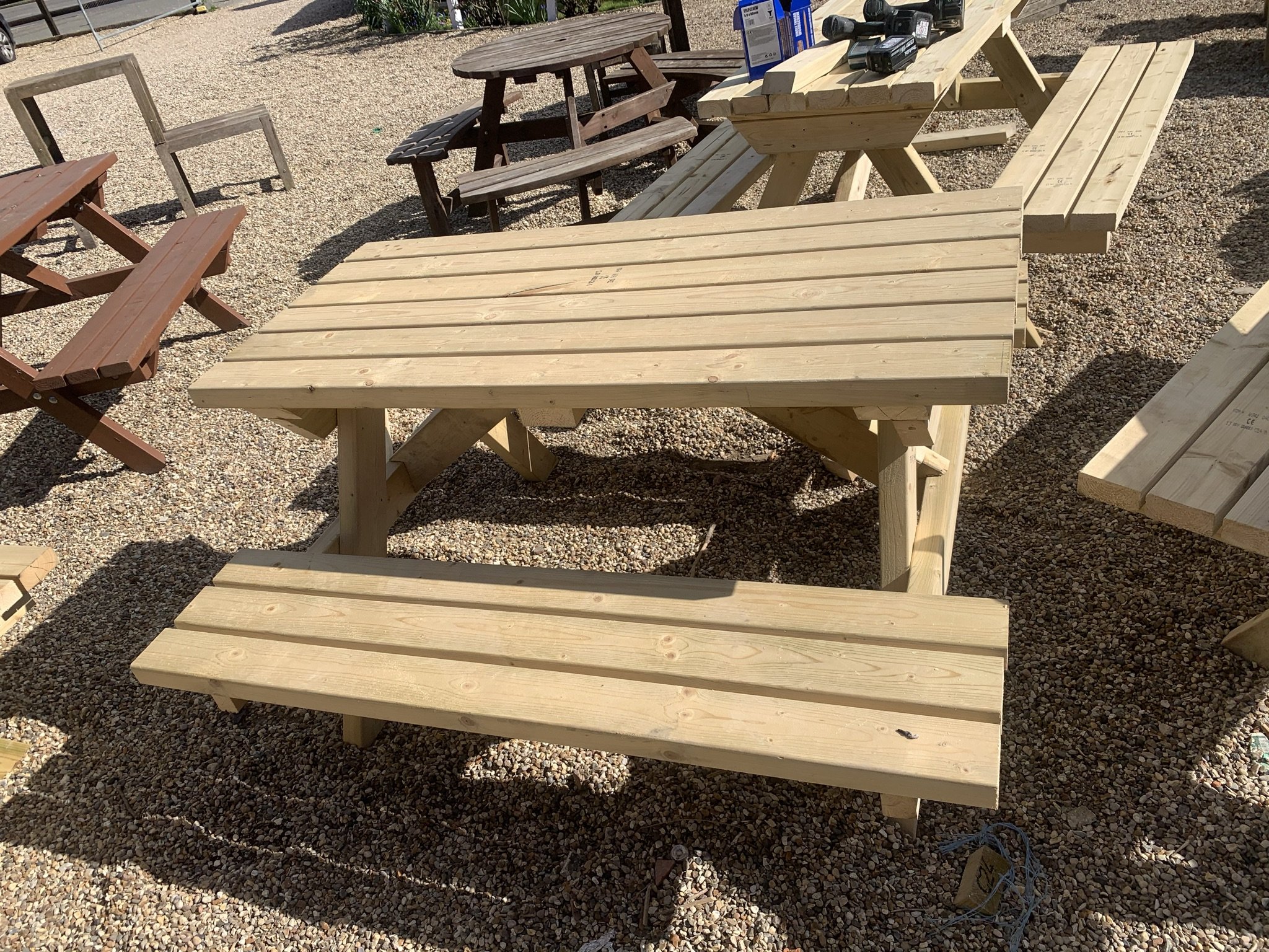 Wooden picnic tables on a gravel surface in outdoor setting