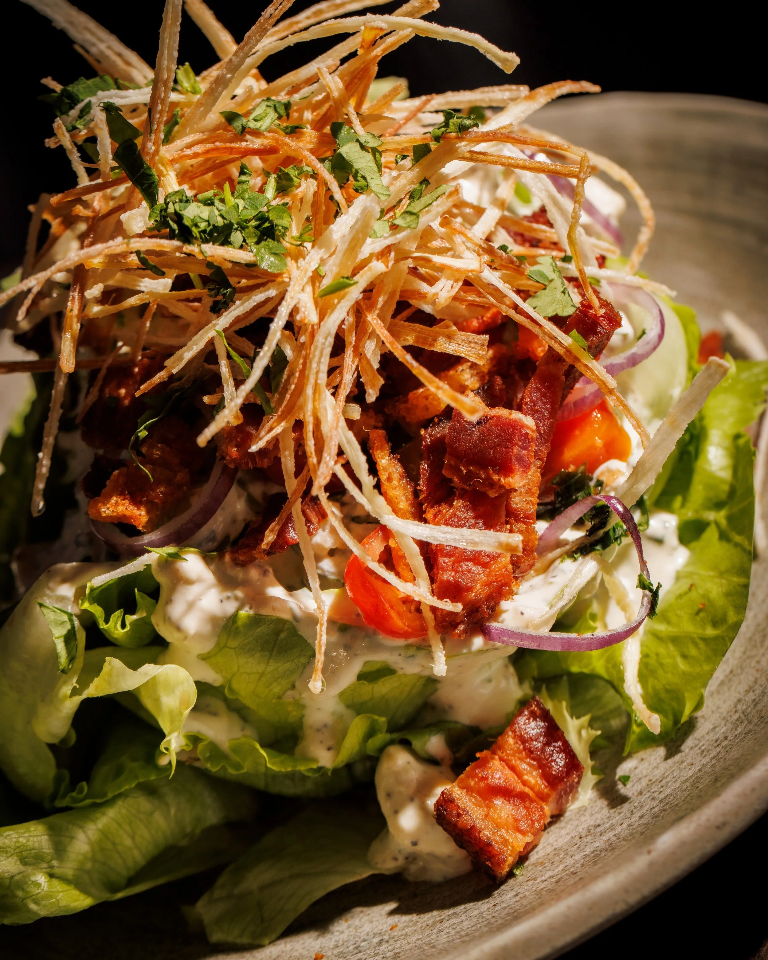This classic Wedge Salad @ The Saint is pure perfection on a plate. A massive wedge of ice-cold iceberg lettuce draped in rich, creamy blue cheese dressing, topped with smoky bacon crumbles, sweet cherry tomatoes, red onion, and a sprinkle of fresh c