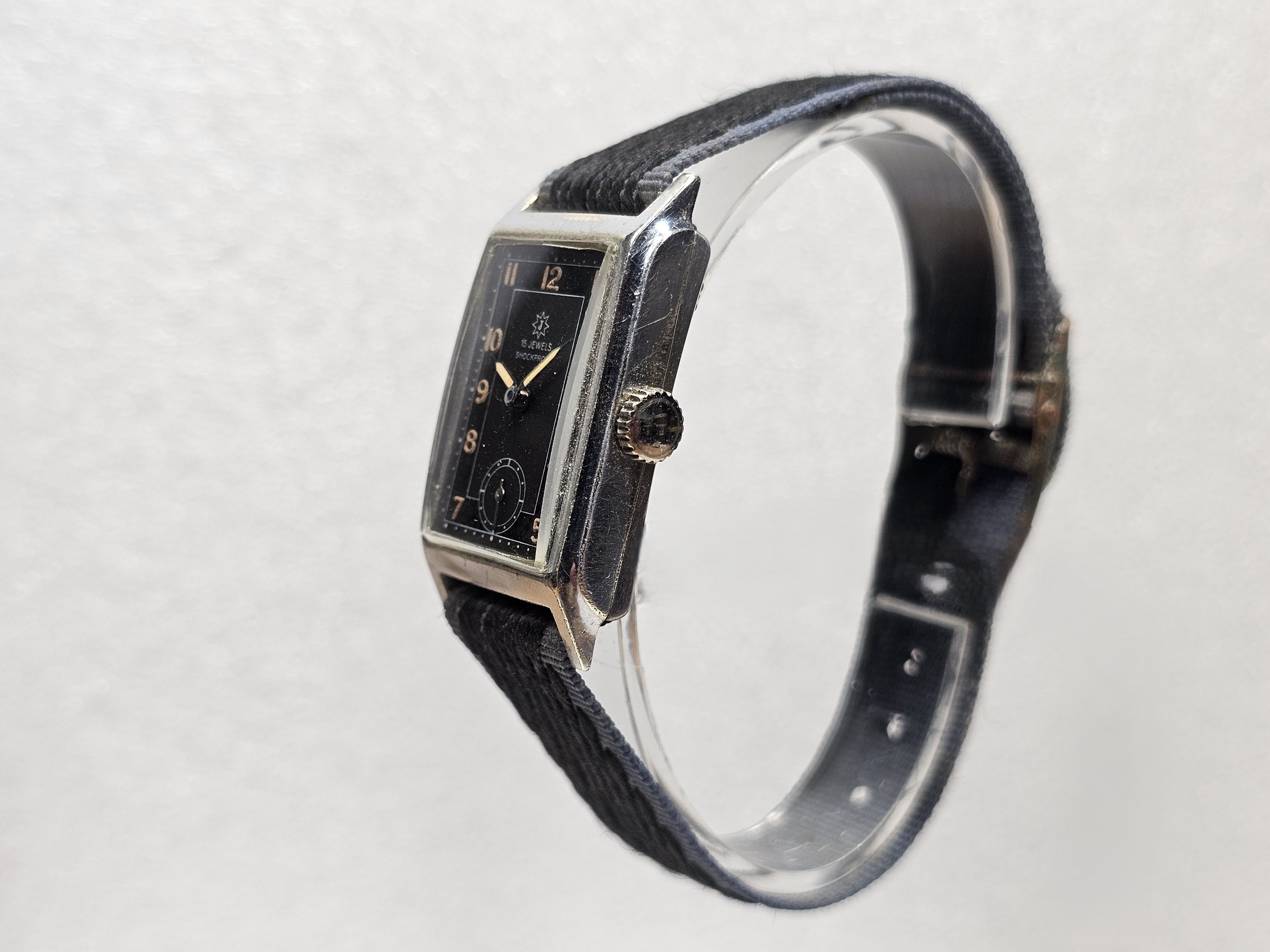 1950s Junghans tank-style dress watch with black gilt dial, sub-seconds register, and chrome-plated rectangular case on black textile strap