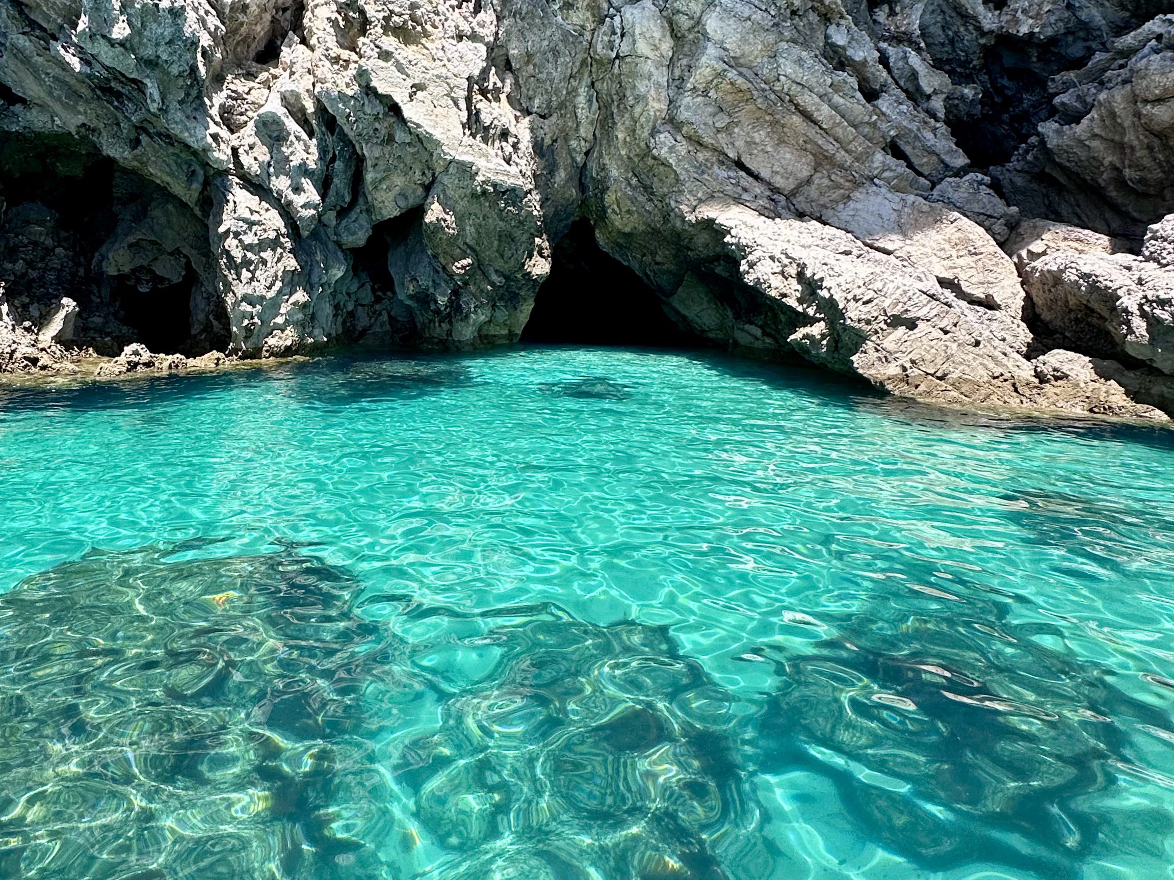 Águas cristalinas azul-turquesa próximas a uma caverna rochosa