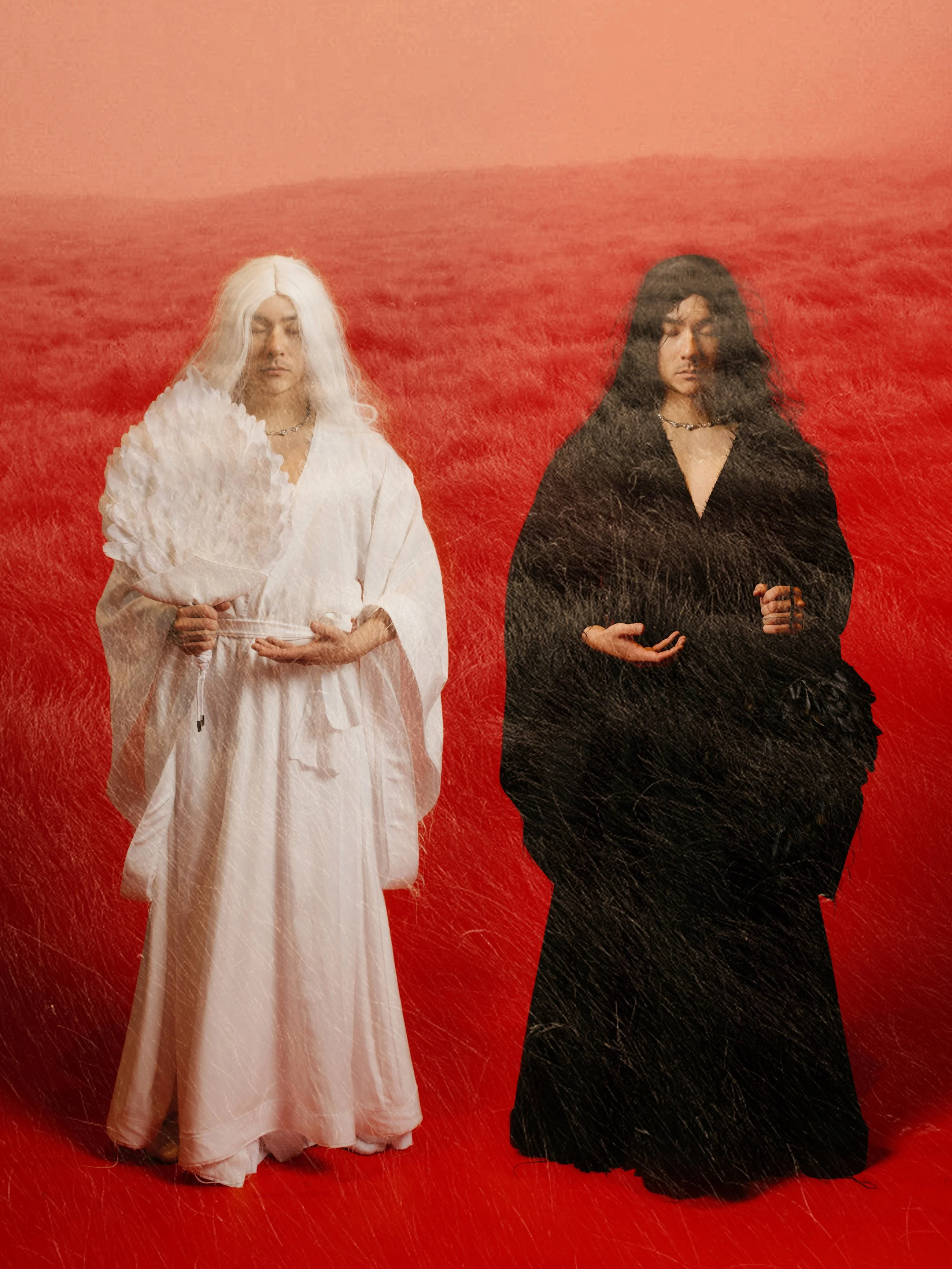 Two individuals standing side by side in front of a red background, one dressed in white holding a fan, and the other dressed in black with long hair, both with their eyes closed.
