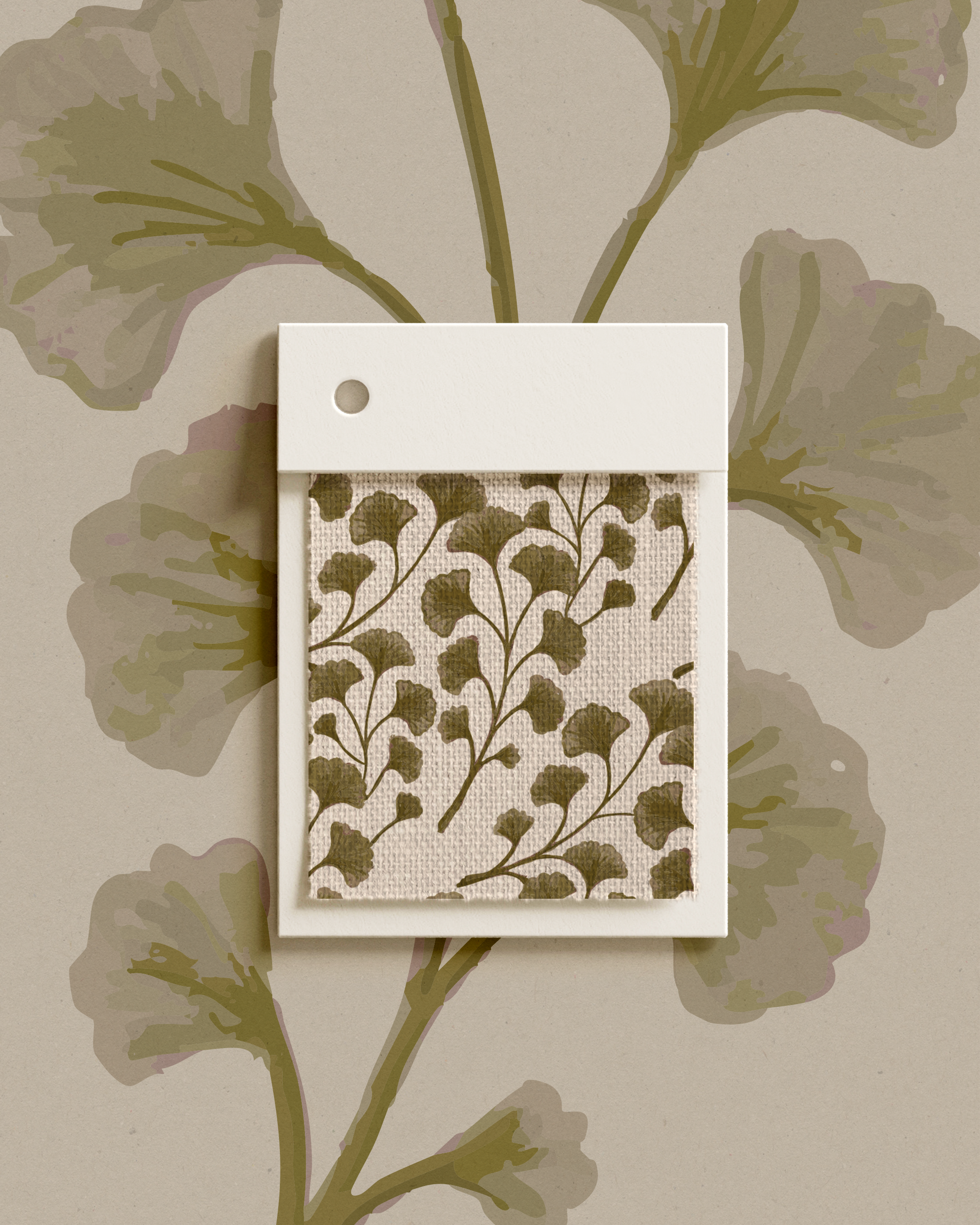 A small fabric sample with a brown ginkgo leaf pattern in a white frame, hanging on a beige wall with a large ginkgo leaf print.