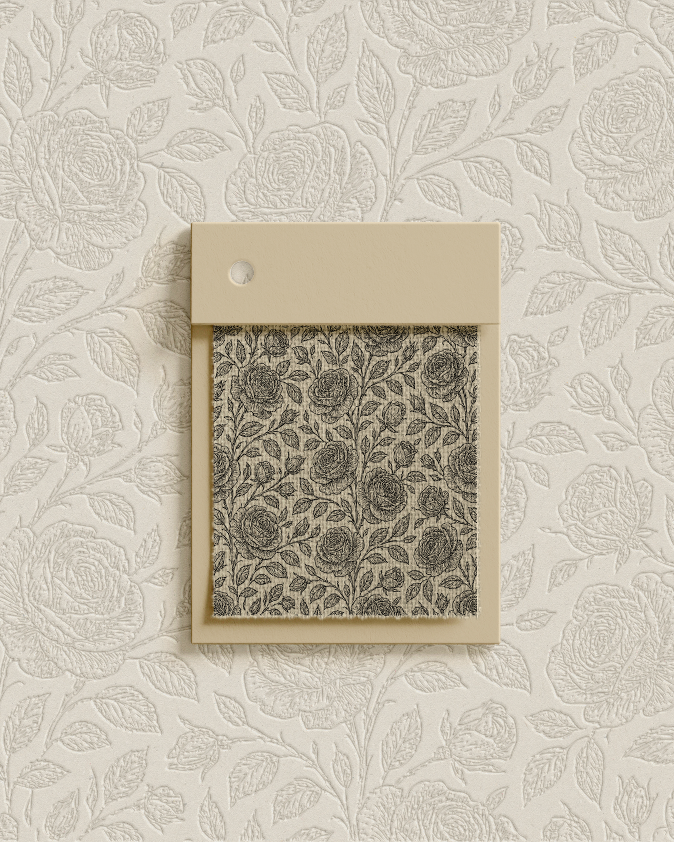 A small fabric sample with a black floral pattern on a beige background, attached to a beige card with a hole in the top left corner, placed against a cream-colored embossed floral wallpaper.