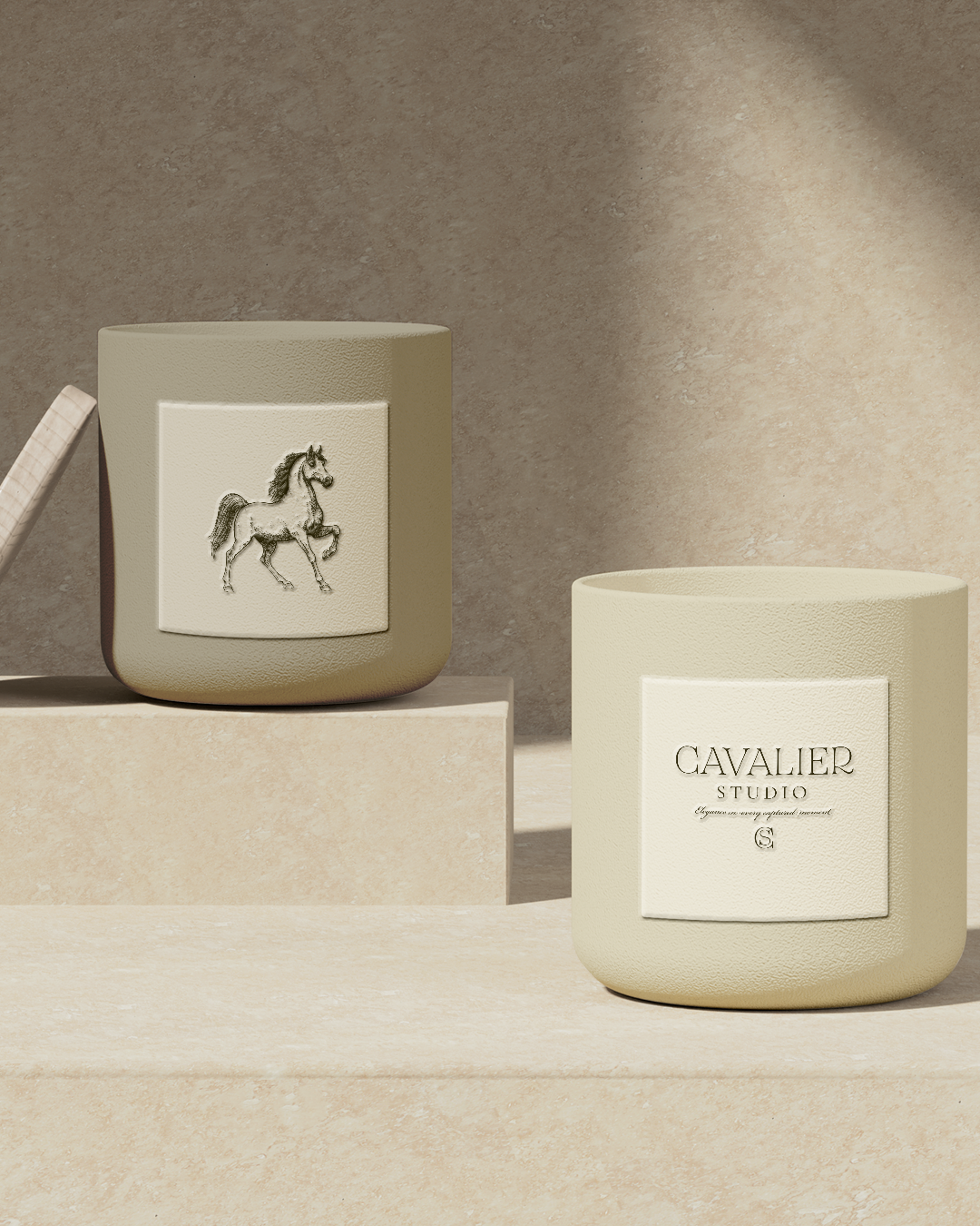 Two beige candles with stylish labels, one featuring a horse illustration, placed on a neutral-toned surface with a textured background and soft lighting.