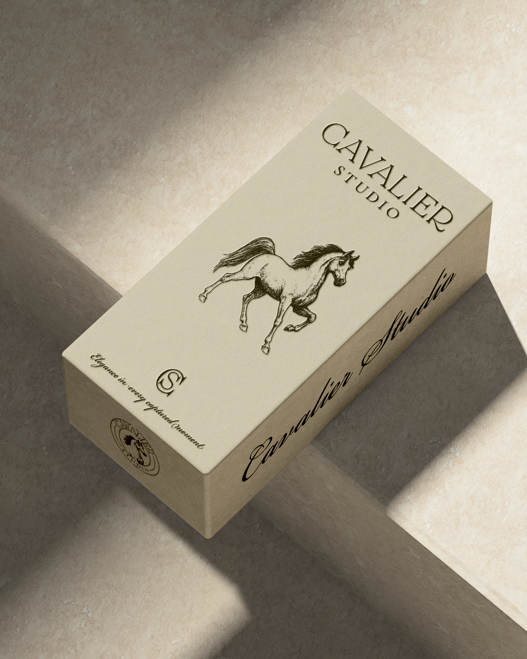 A box labeled CAVALIER Studio with a sketch of a running horse on it, placed on a tiled surface with shadows.